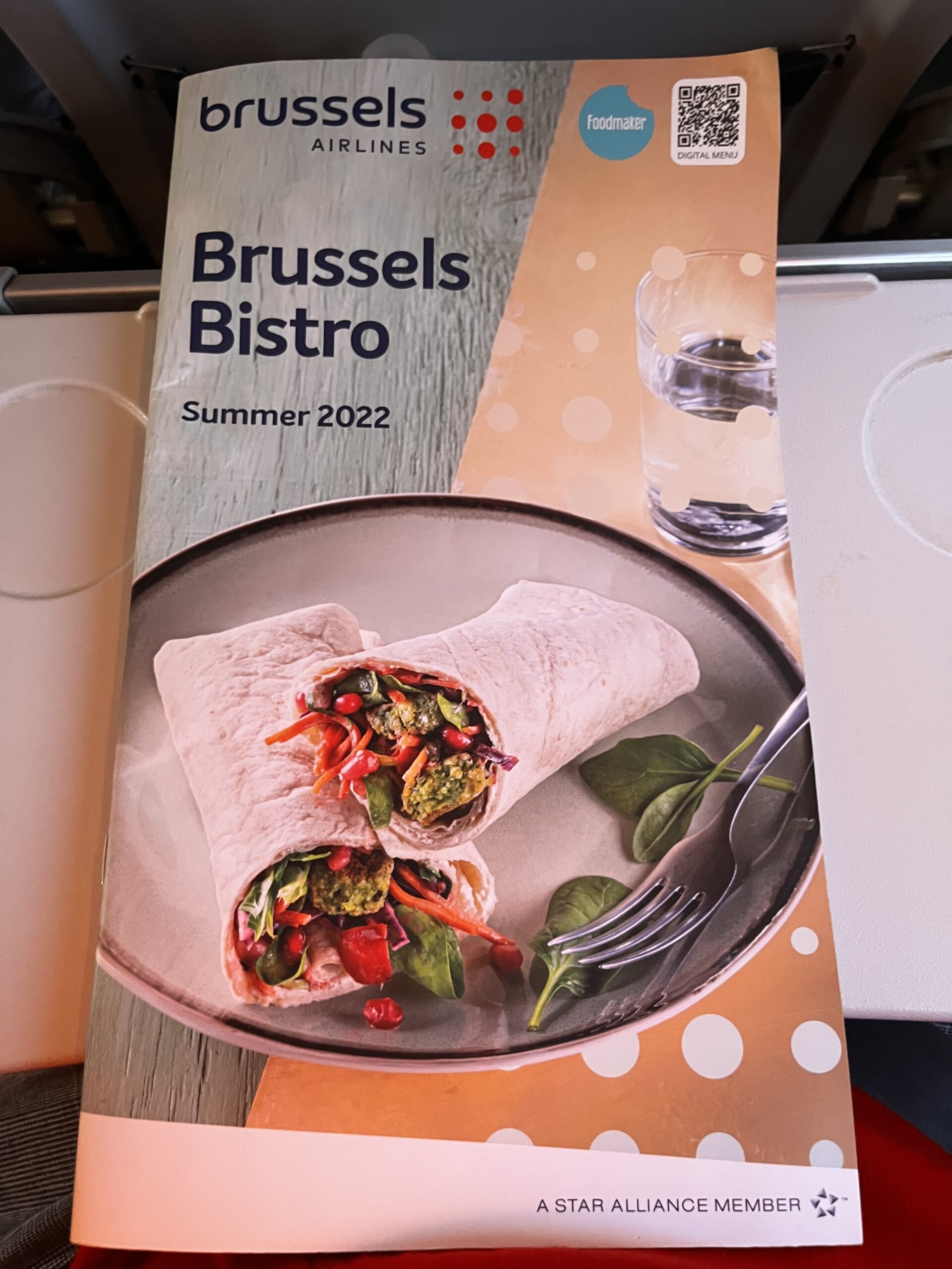 Brussels Airlines Bordmenü 'Brussels Bistro Summer 2022' mit Wrap-Foto auf dem Tisch im Flugzeug.