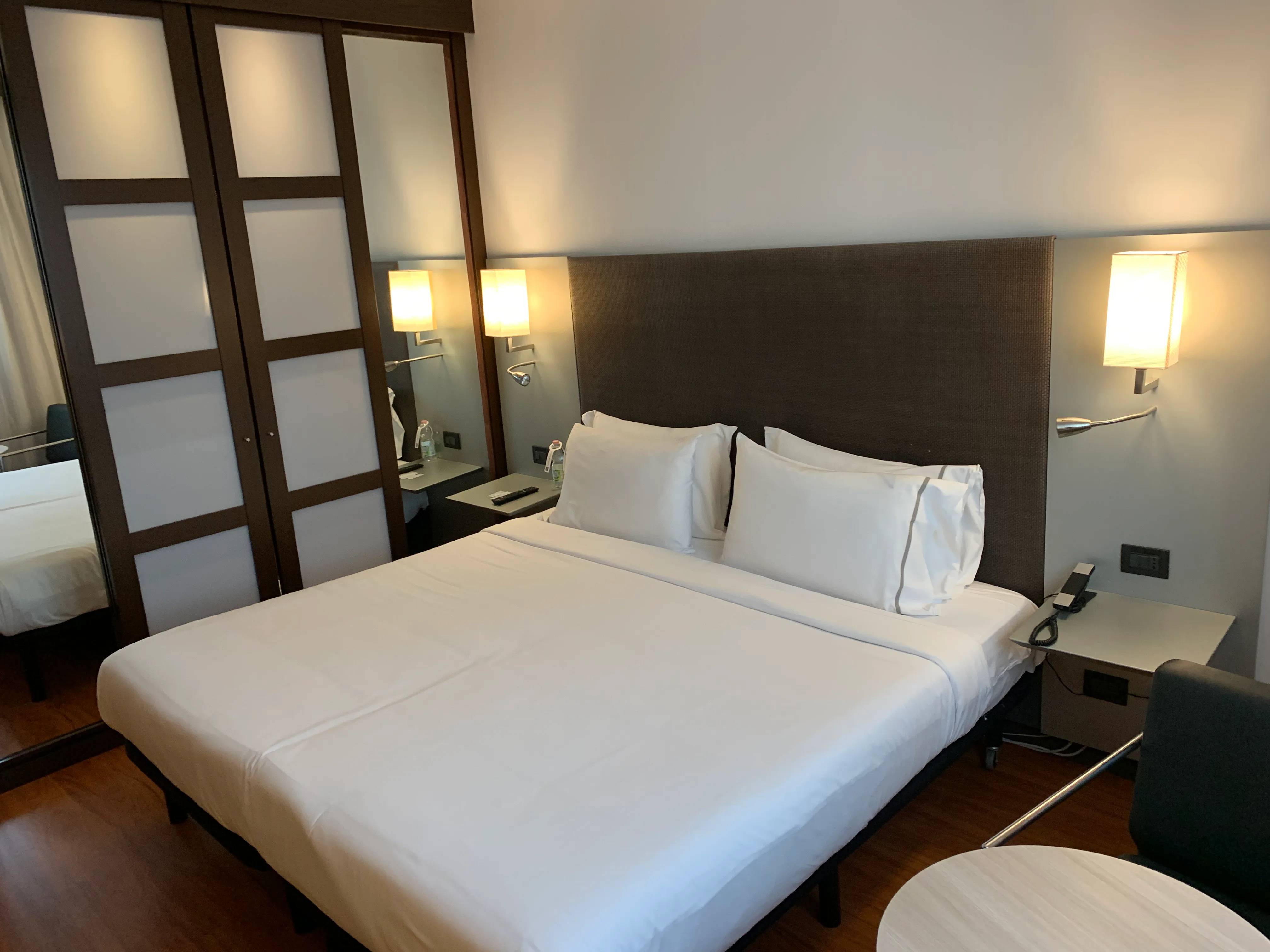 Hotelzimmer mit Doppelbett und grauem Bettbezug