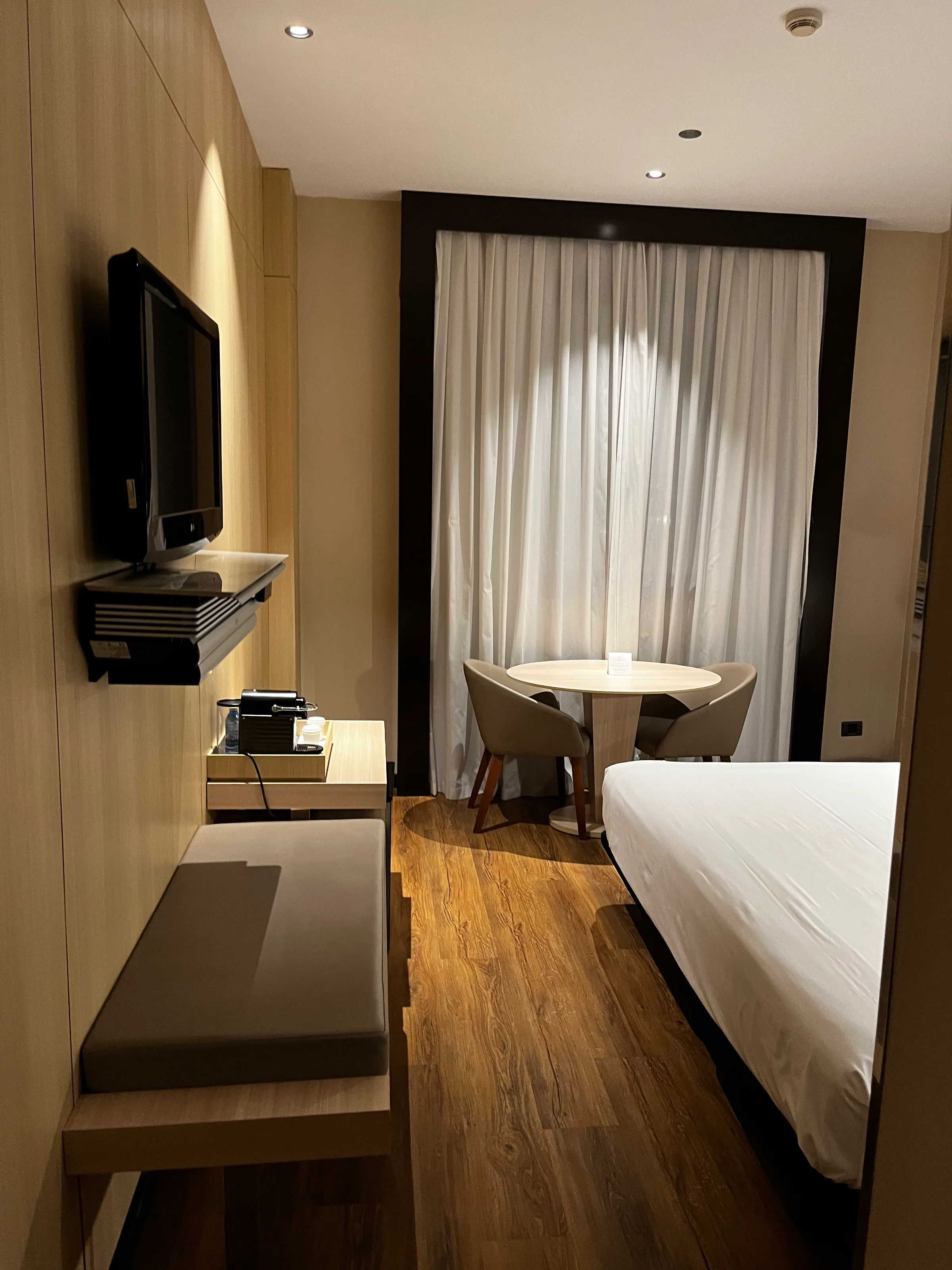 Hotelzimmer mit Doppelbett und Tisch vor Fenster