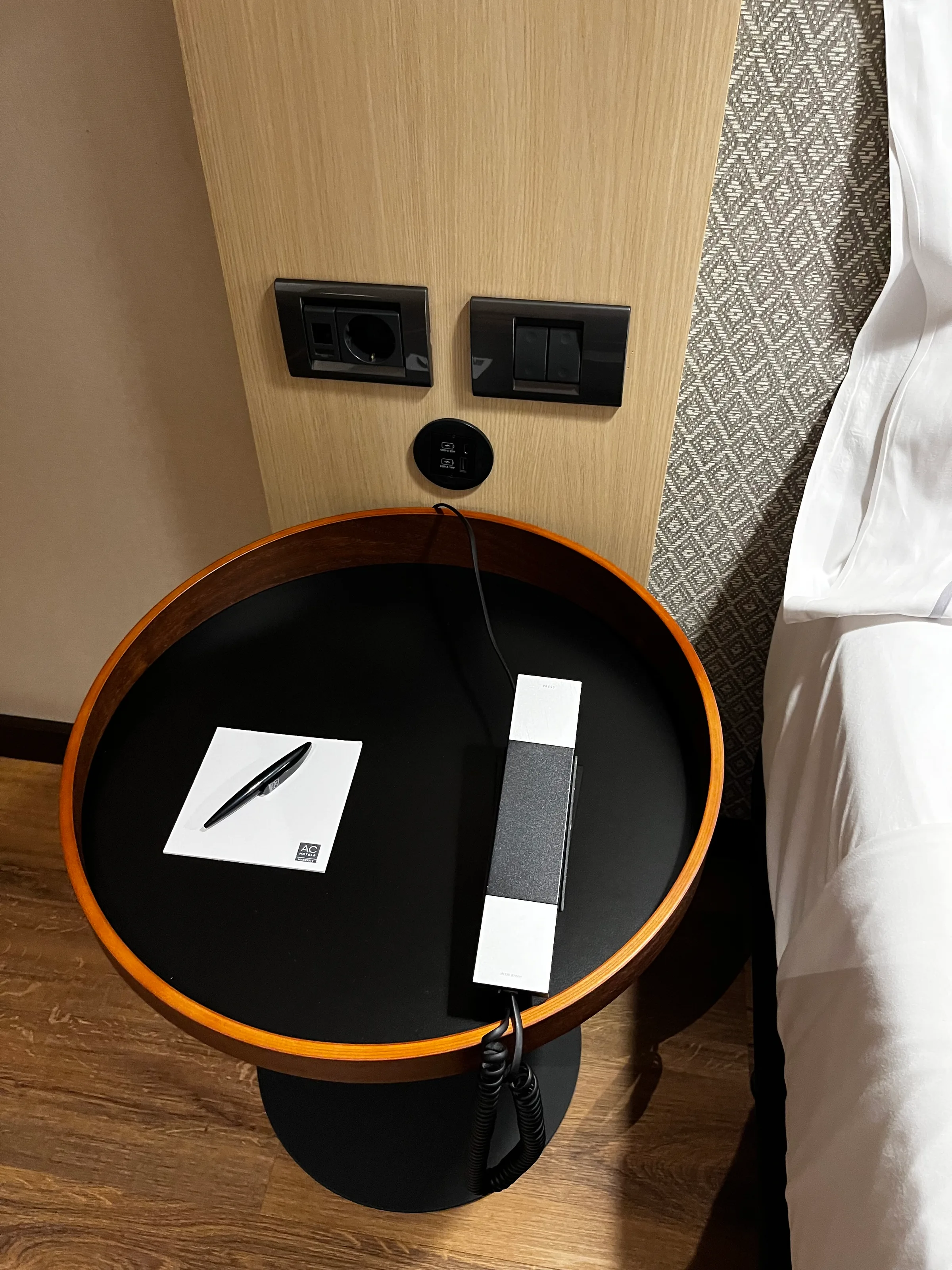 Hotelnachttisch mit Kabel und Papier auf Holzpaneel