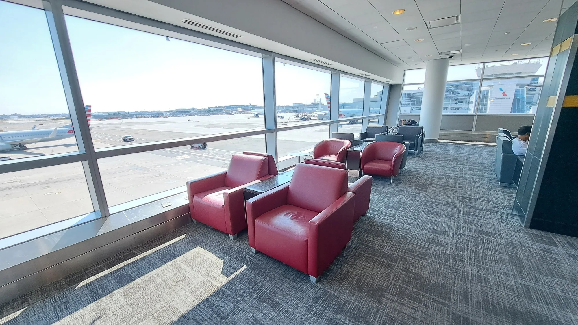 Lounge mit roten Sesseln und Blick auf Flugzeuge am Flughafen