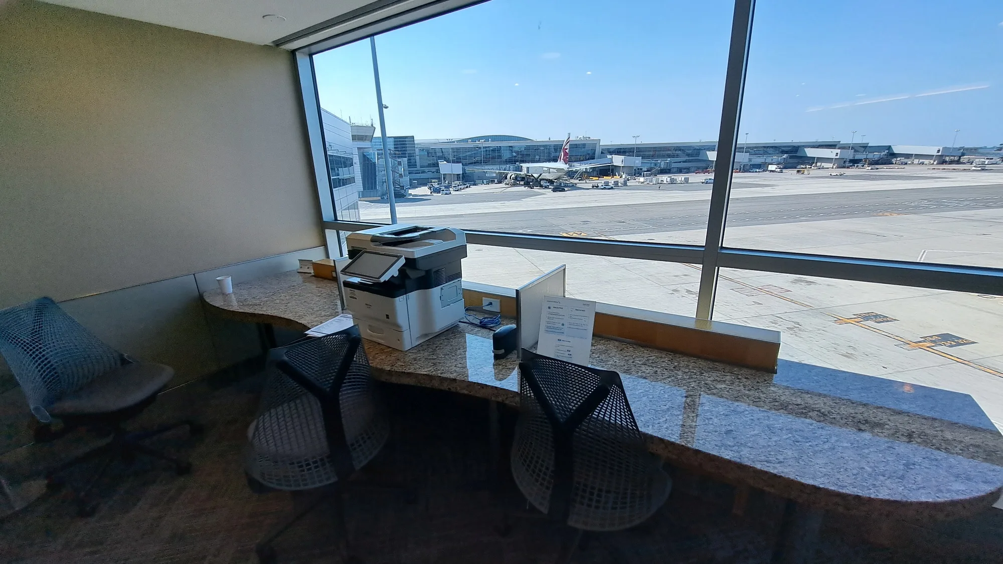 Lounge mit Tischen und Stühlen am Fenster mit Flughafenblick