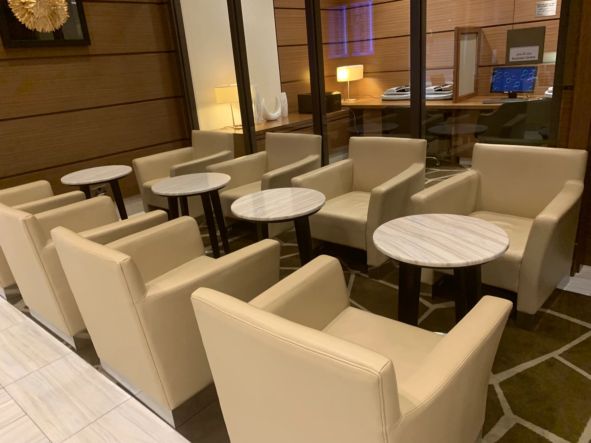 Business Class Lounge mit weißen Sesseln und runden Tischen