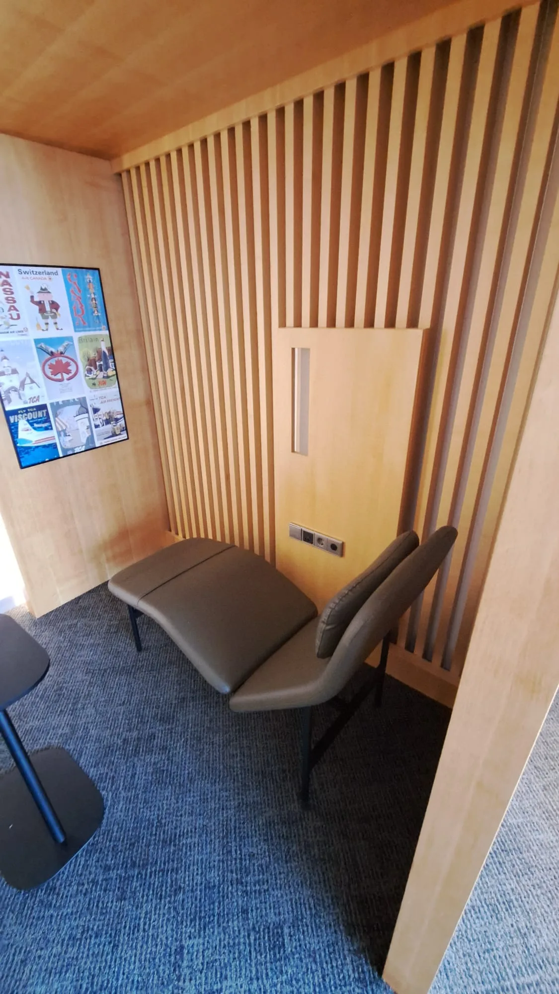 Einzelner Sitzplatz in einem Flughafen-Lounge mit Holzwänden und Poster an der Wand