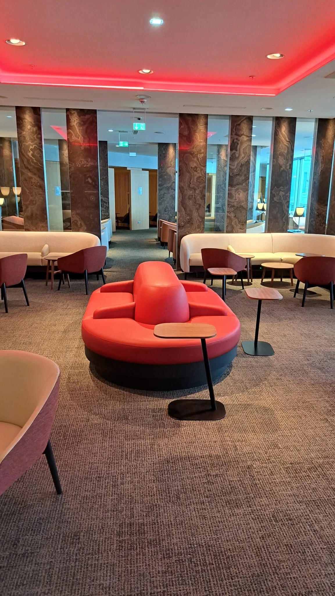 Runde rote Sitzgruppe im Flughafenlounge mit Couchtischen