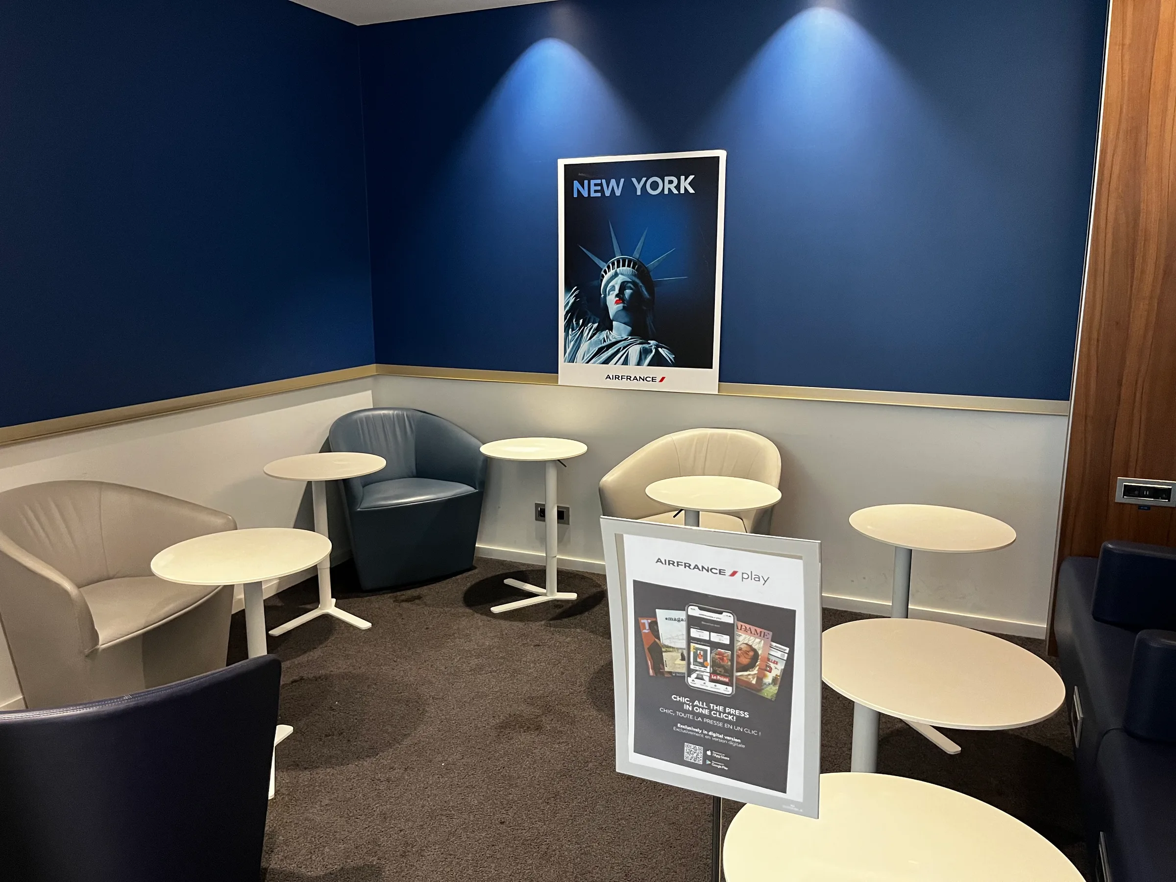 Lounge mit Sesseln und Tischen in blauem Raum