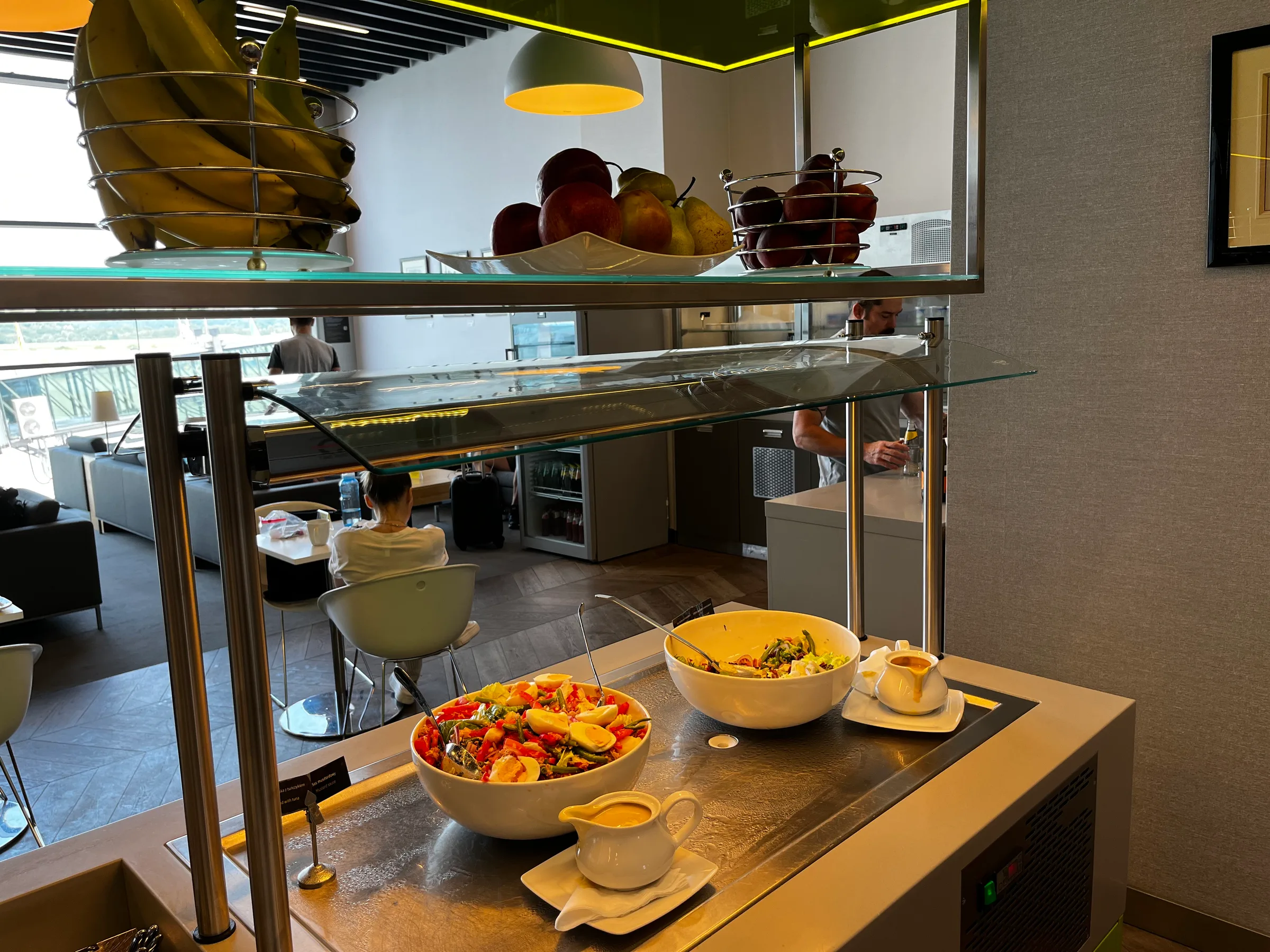 Frühstückstablett mit Salat und Obst auf Glastheke im Flughafenlounge