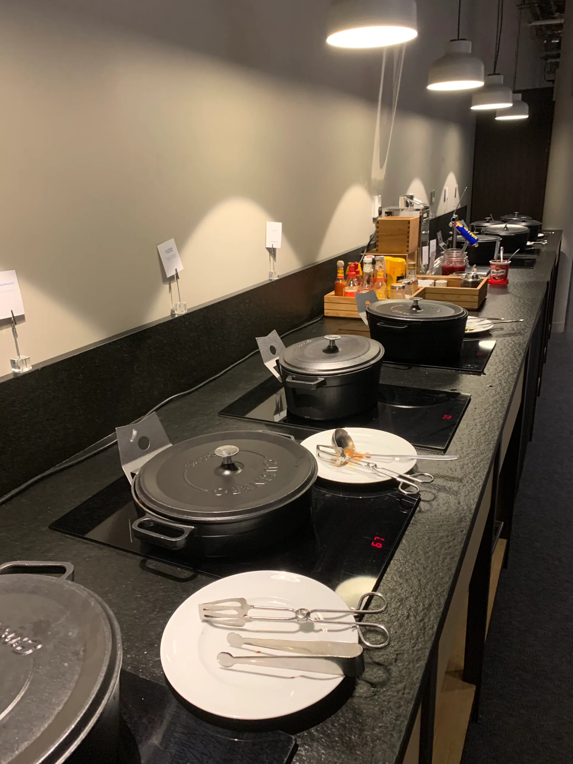 Buffet mit Kochtopfen und Geschirr auf schwarzer Arbeitsplatte