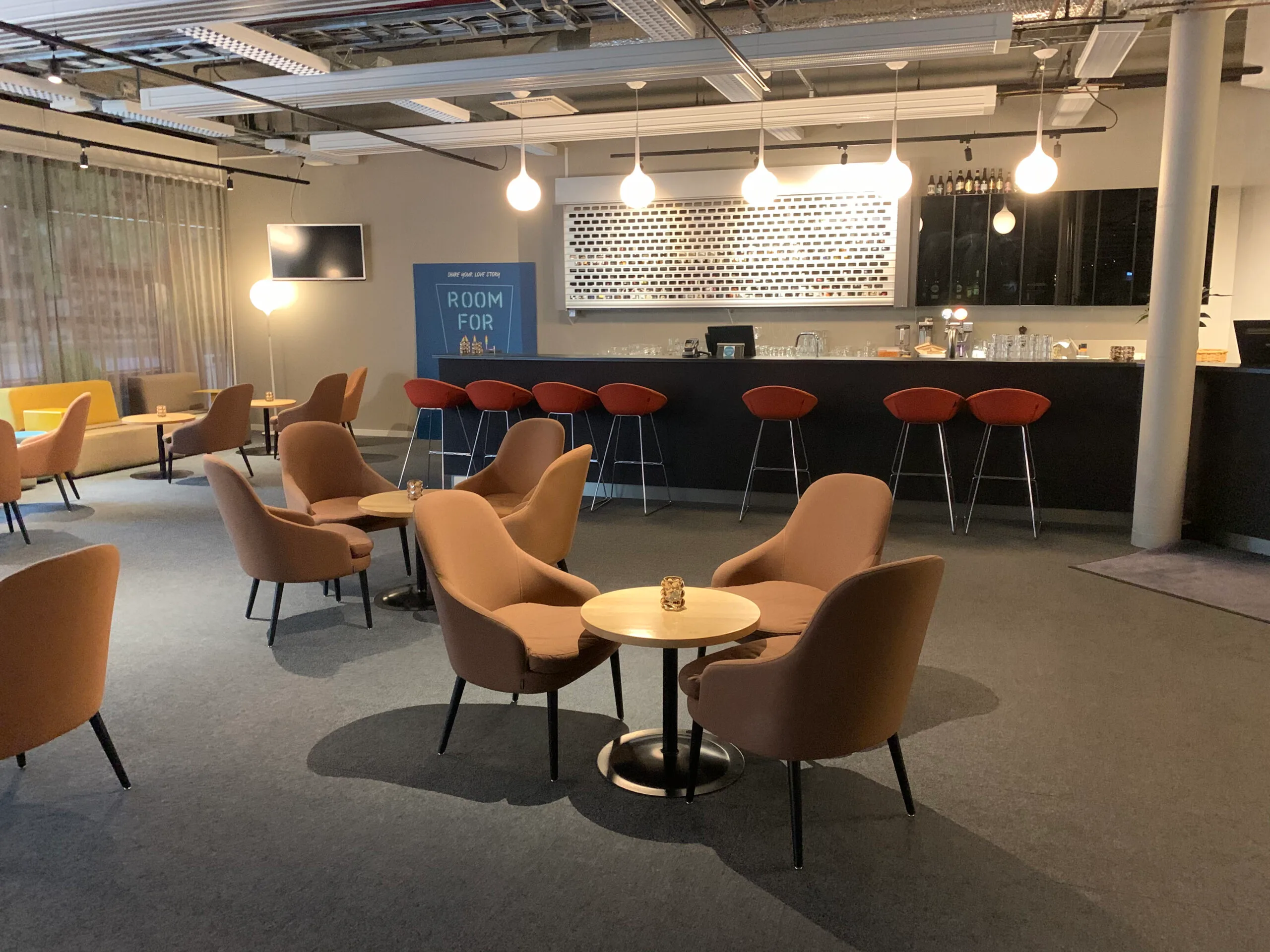 Loungebereich mit Sesseln und Bar im Flughafenhotel