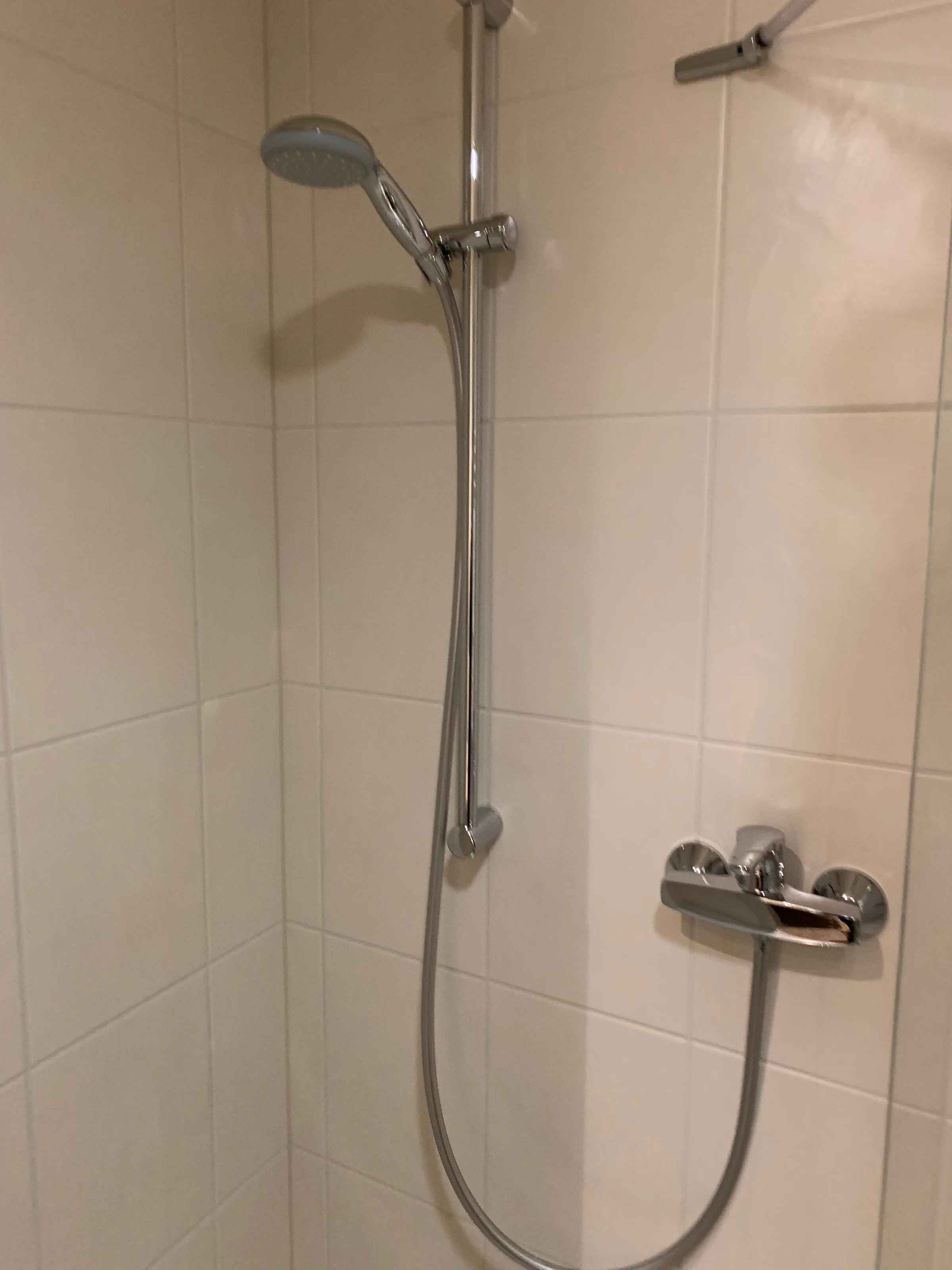 Duscharm mit Handbrause und Wasserhahn an der Wand