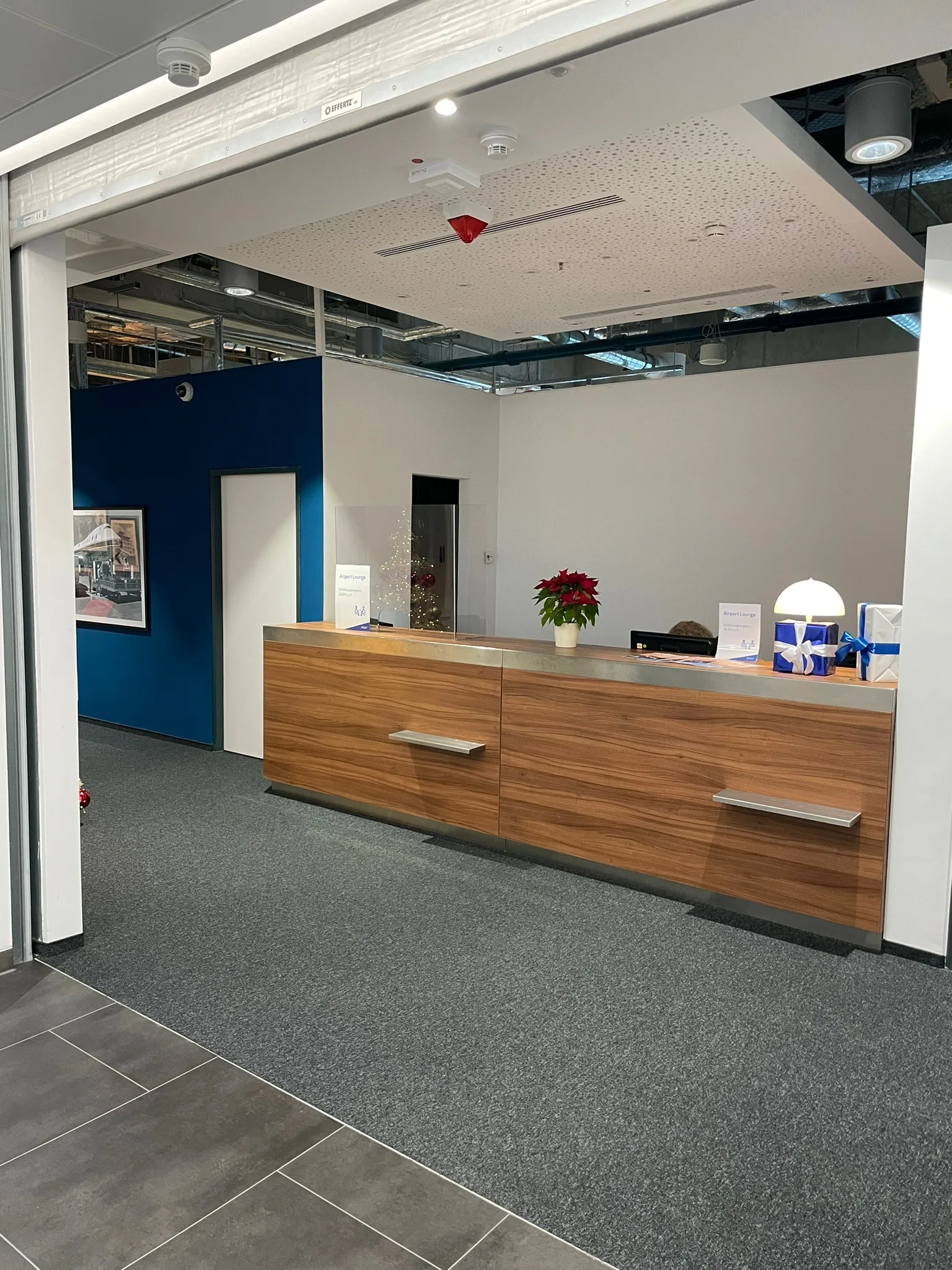 Rezeption mit Holztisch und Pflanze im Flughafenlounge