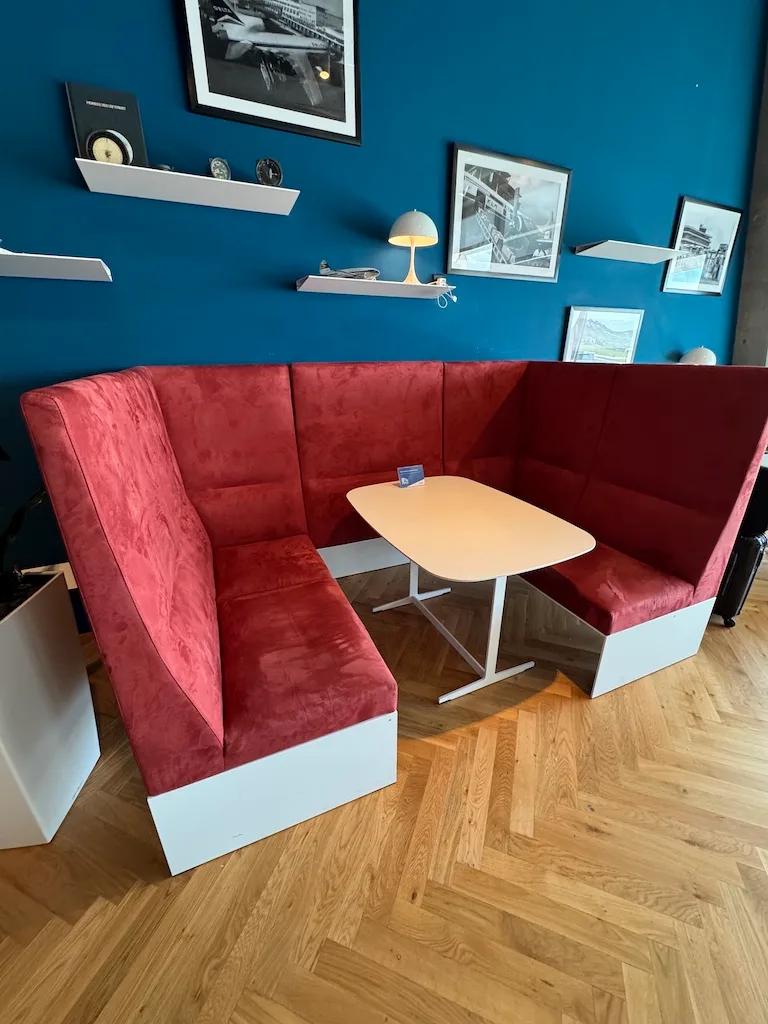Rotvelourssofa mit Tisch vor blauer Wand