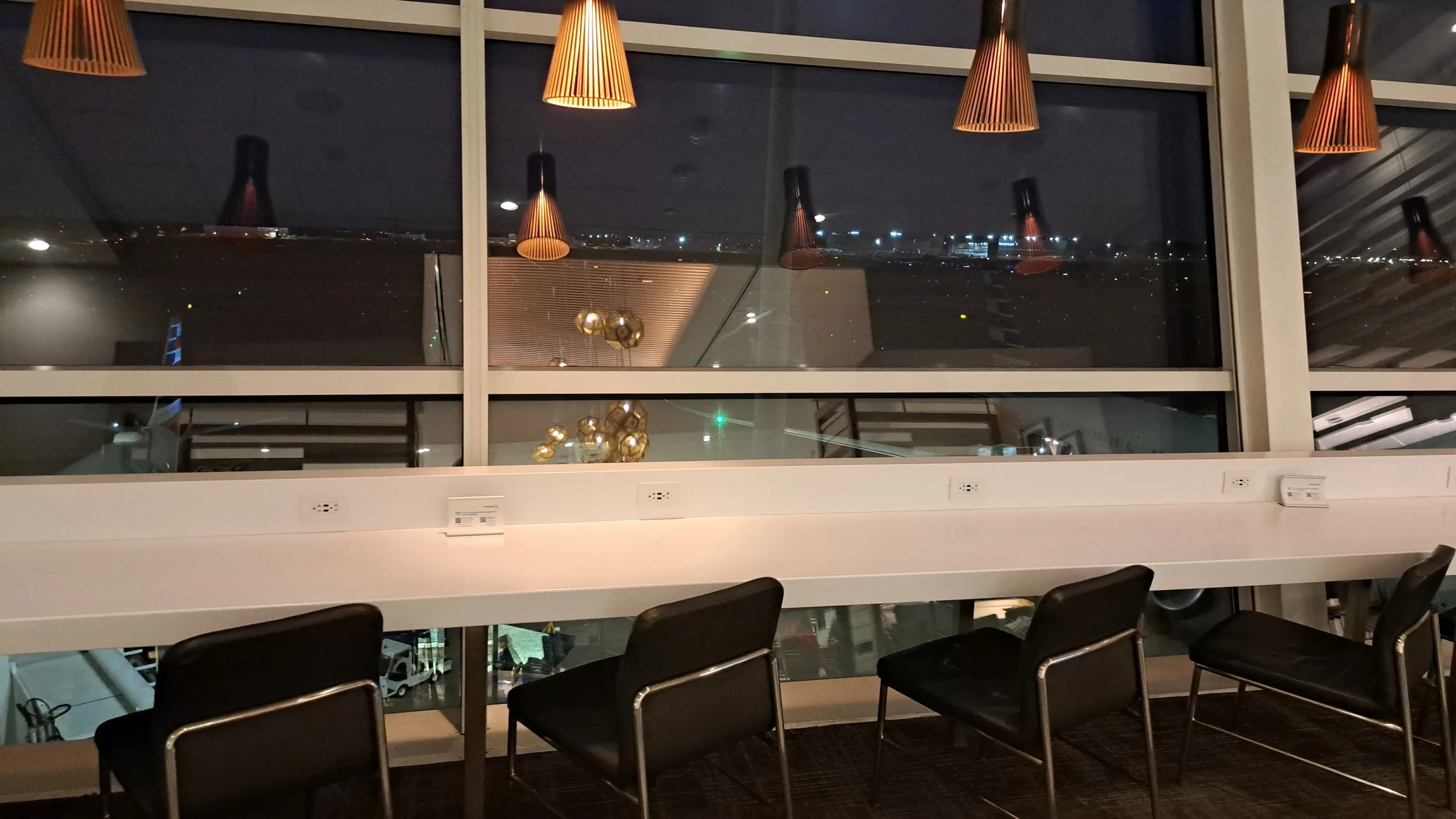 Lounge mit Stühlen und Fensterfront zur Flughafenerweiterung