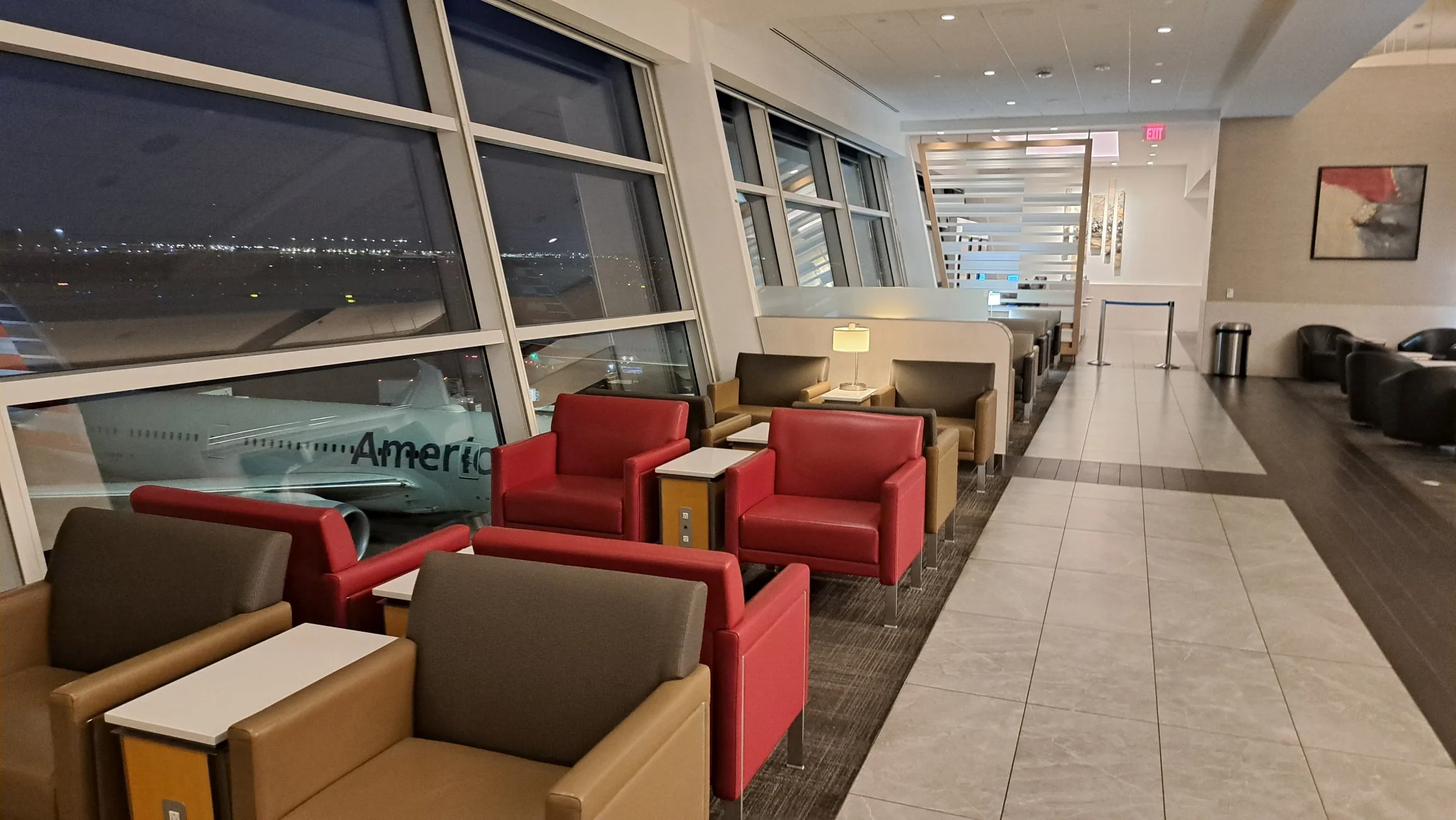 Lounge mit Sesseln und Tischen, Blick auf Flugzeug im Hintergrund
