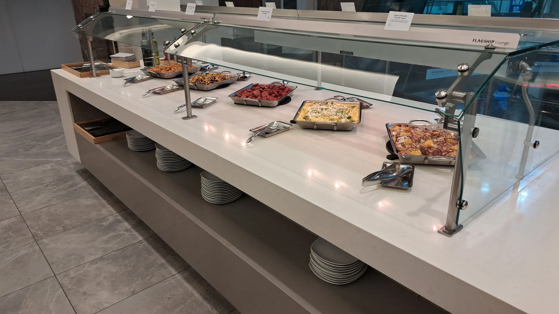 Buffet mit verschiedenen Speisen und Tellern im Flughafenlounge