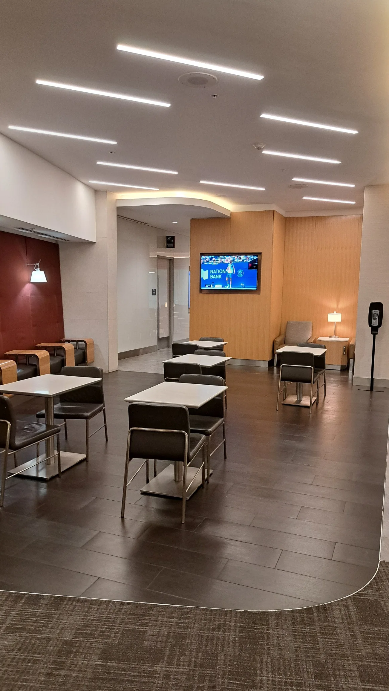 Lounge mit Tischen und Stühlen, Fernseher im Hintergrund