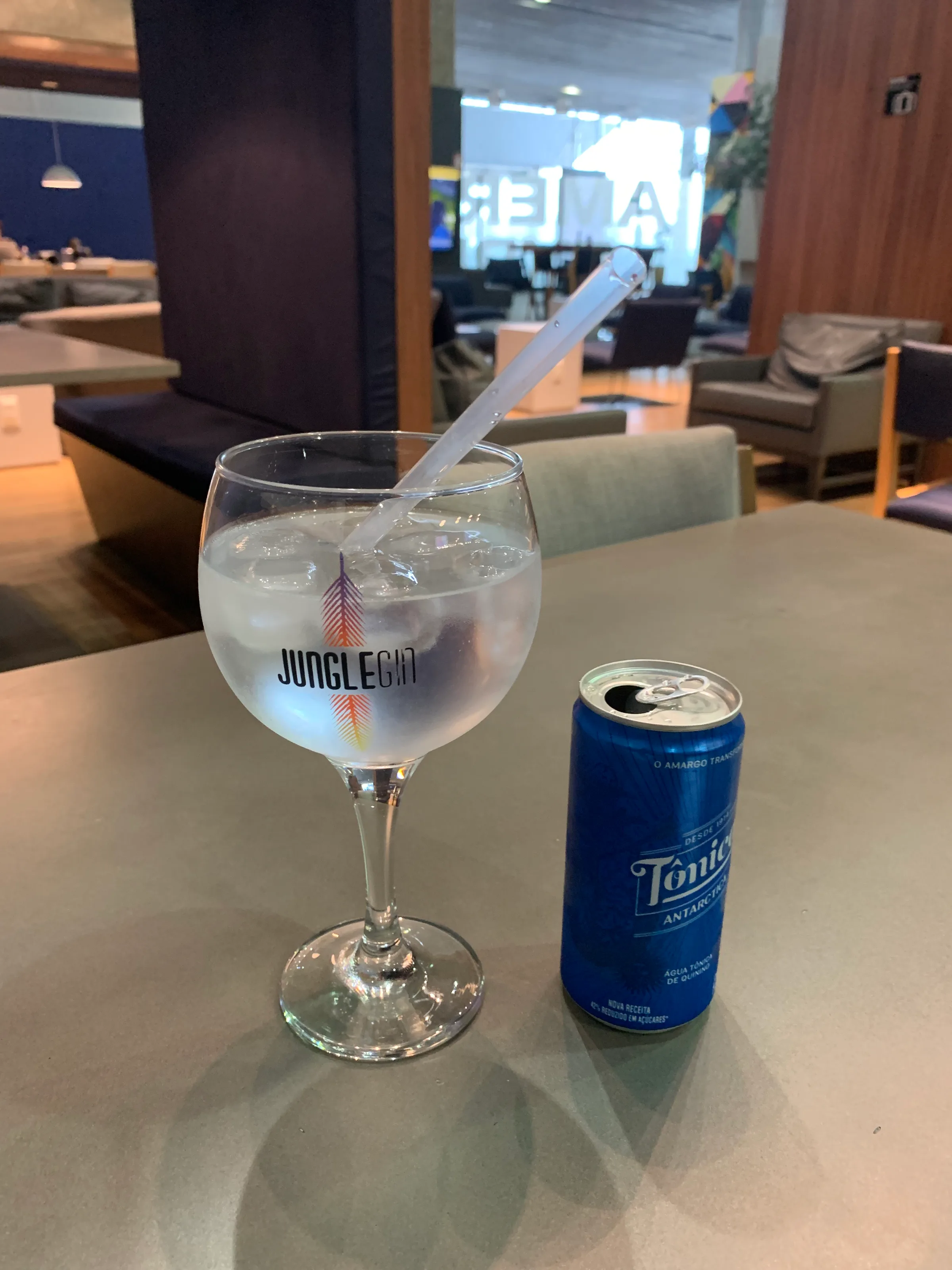 Gin-Tonic-Glas mit Strohhalm auf Tisch im Lounge