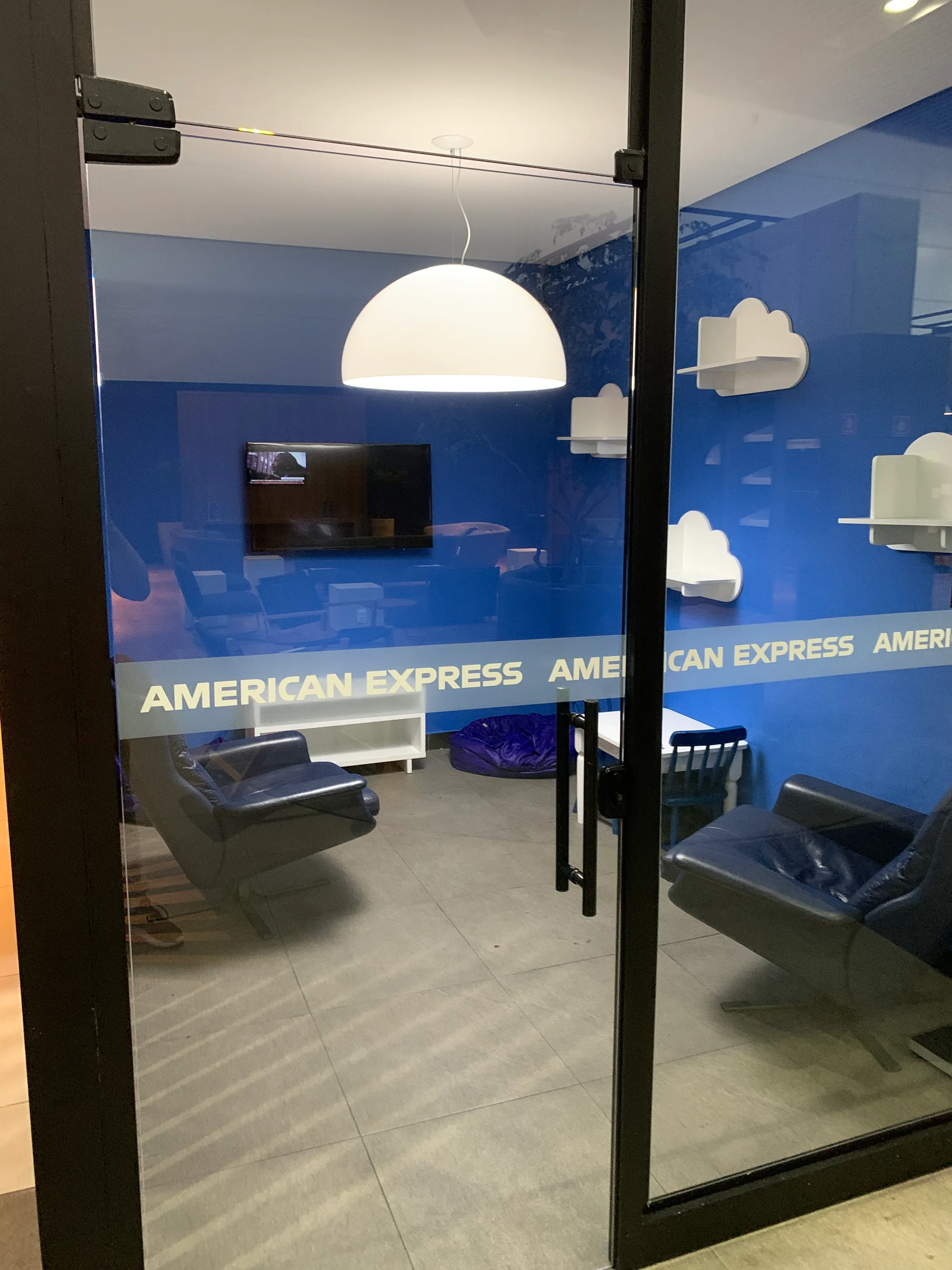 VIP-Lounge mit Sesseln und Fernseher im American Express Design