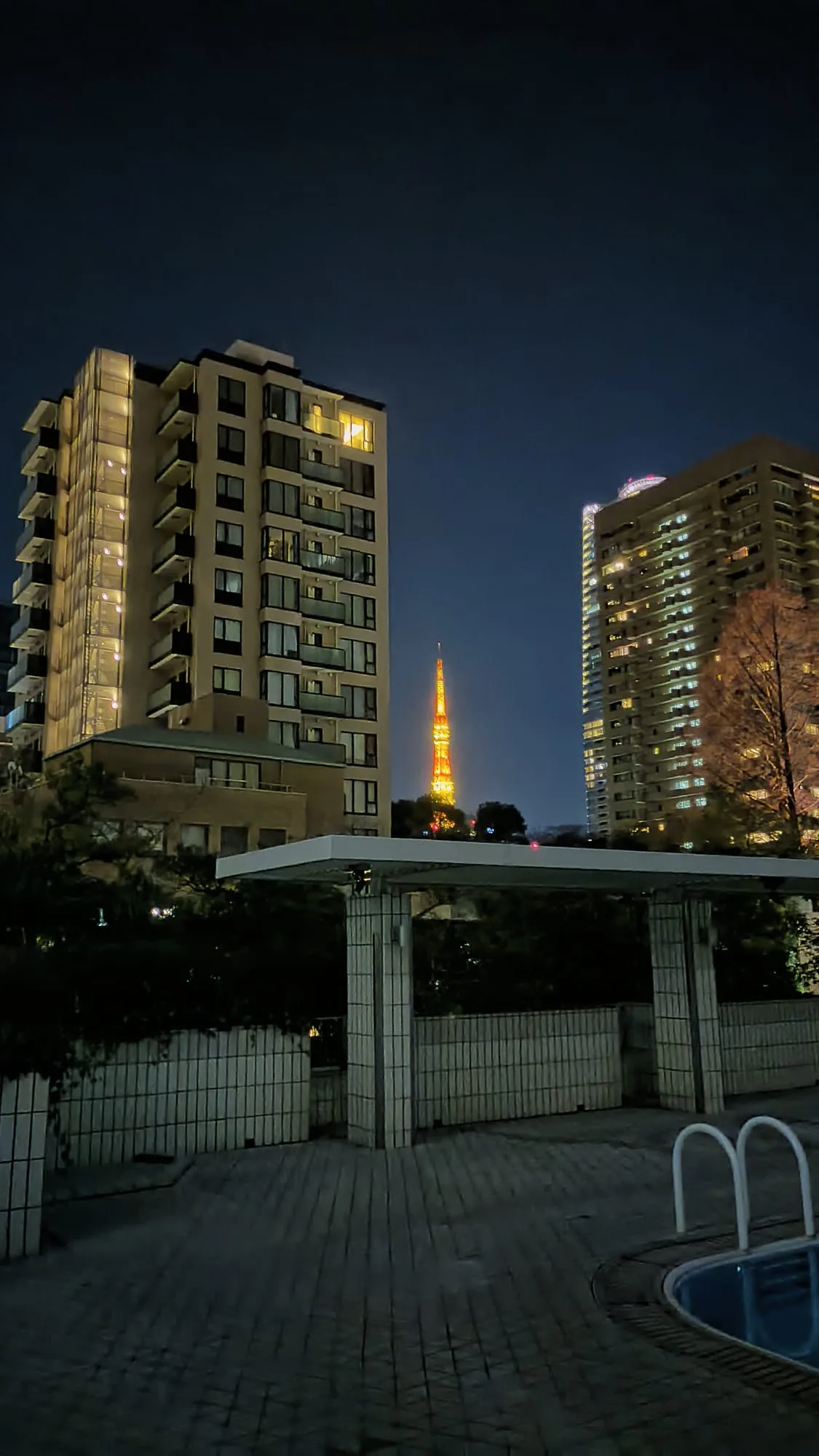 Nachtansicht eines Hochhauses mit beleuchteter Fassade und Blick auf den Tokyo Tower