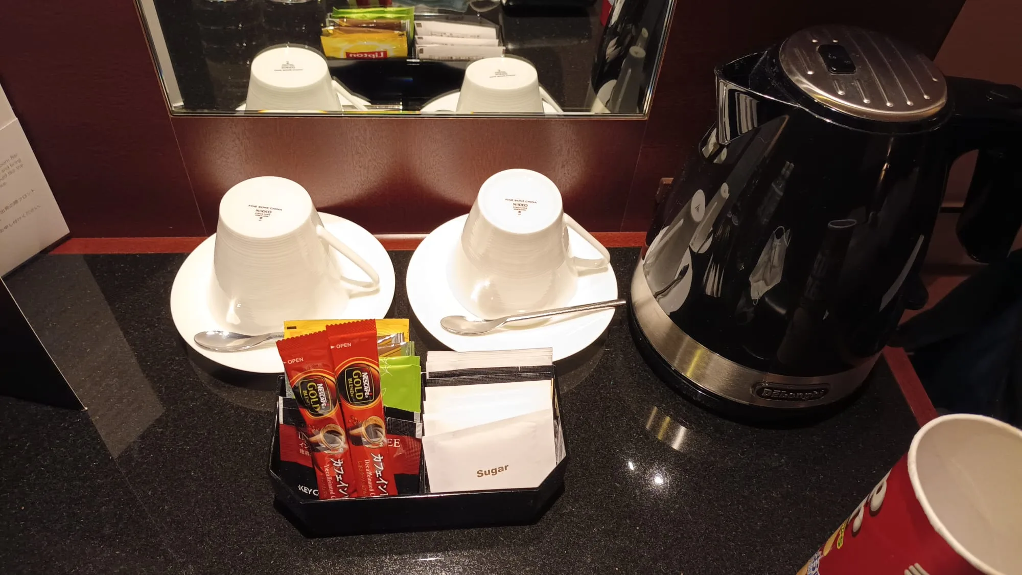 Hotelzimmerecke mit Kaffeemaschine, Tassen und Zuckerpäckchen