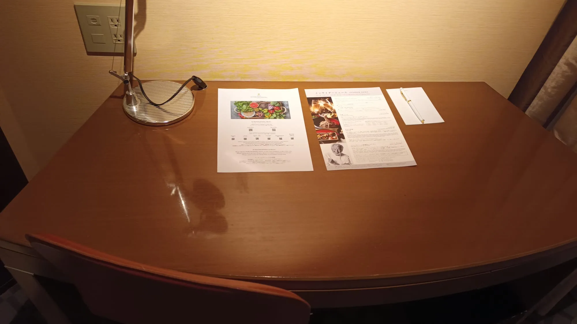 Hotelzimmer mit Tisch, Dokumenten und Lampe