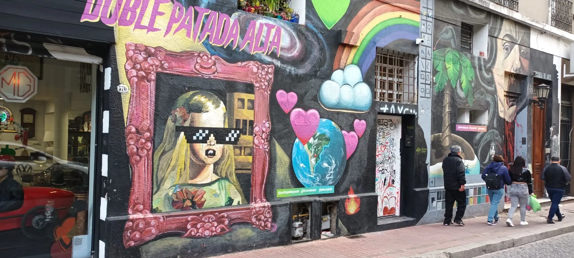 Graffiti-Malerei an einer Hauswand mit Bilderrahmen und Herzsymbolen