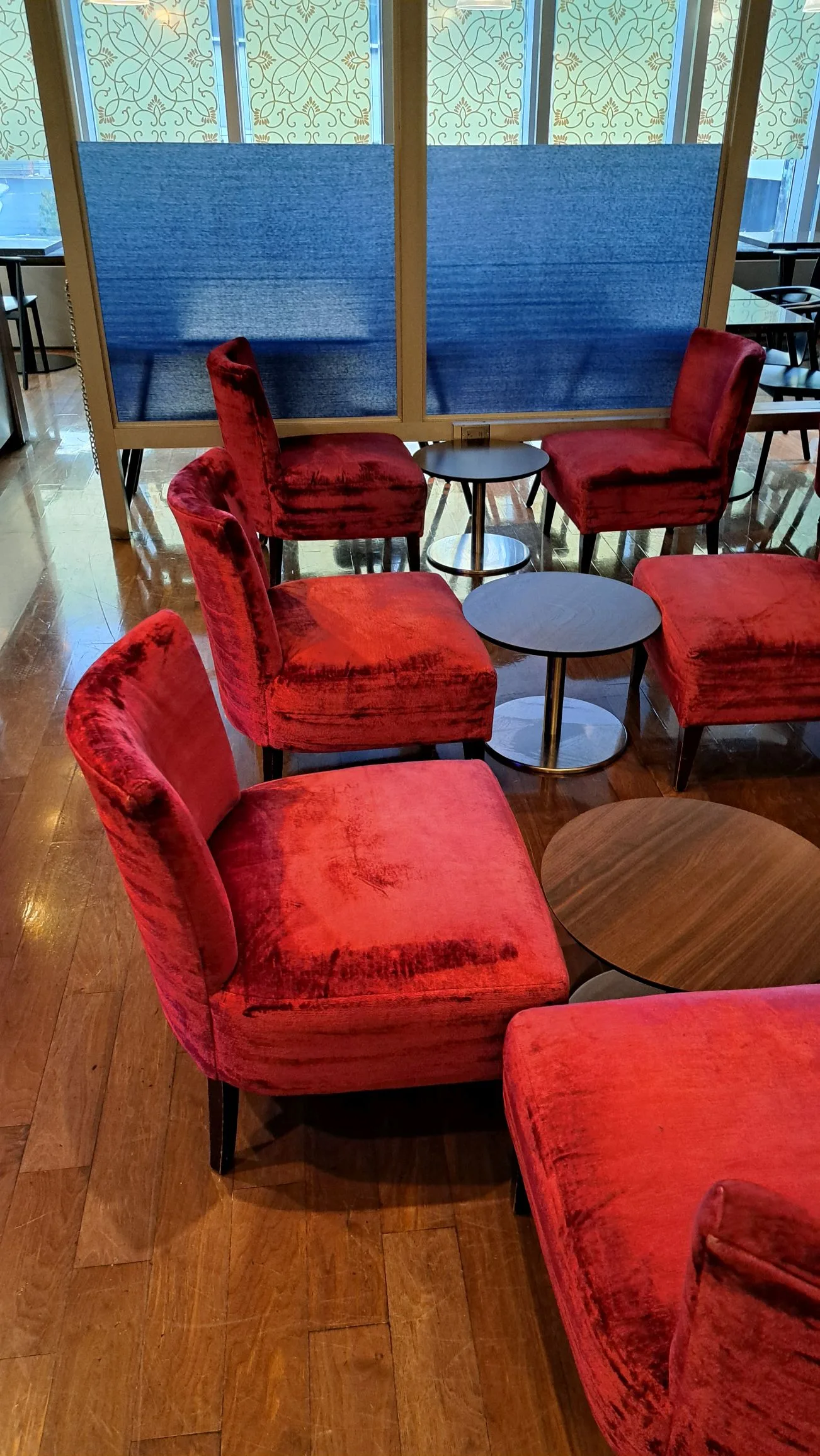 Rote Samtstühle und Beistelltische im Loungebereich