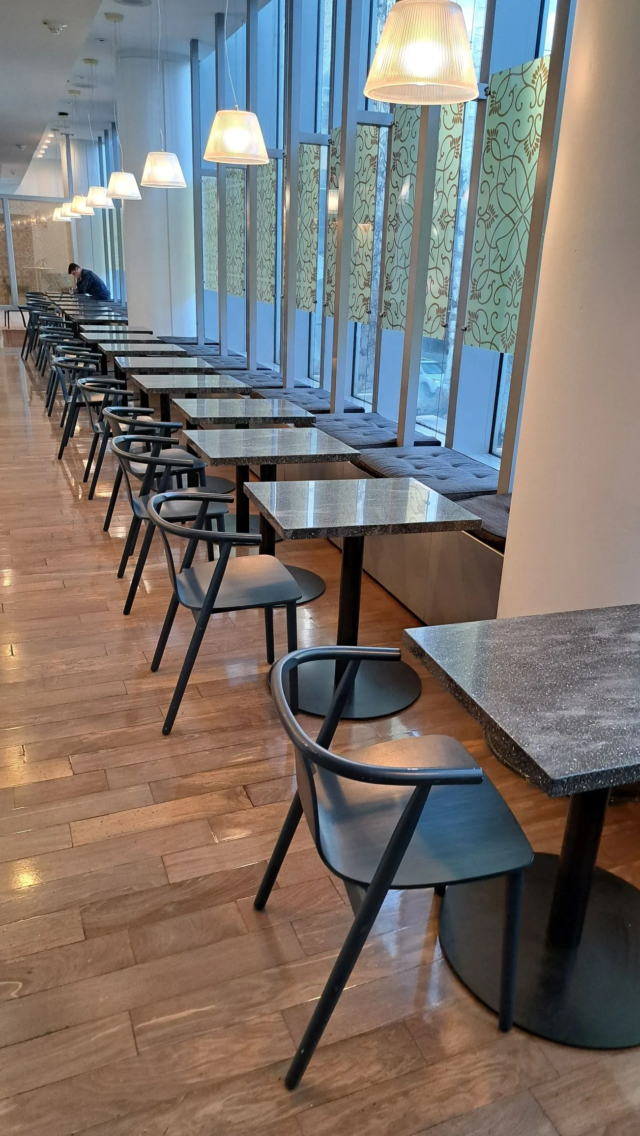 Reihen von Tischen und Stühlen in einem Flughafenlounge mit großen Fenstern