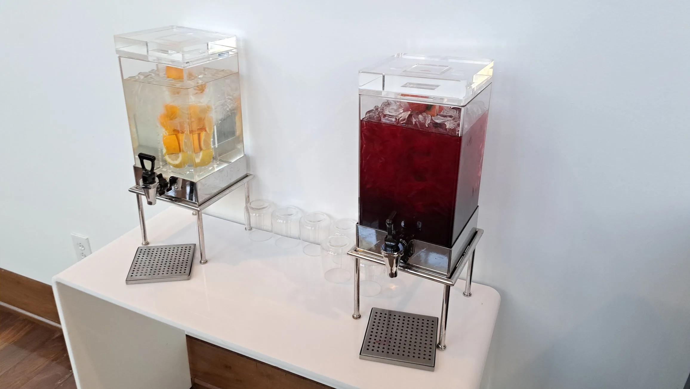 Getränkeautomaten mit Eiswürfeln und Früchten auf weißem Tisch