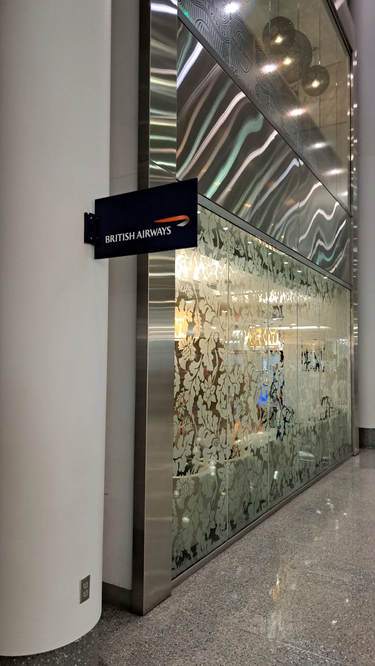 British Airways-Schild an Wand mit Glaswand im Hintergrund