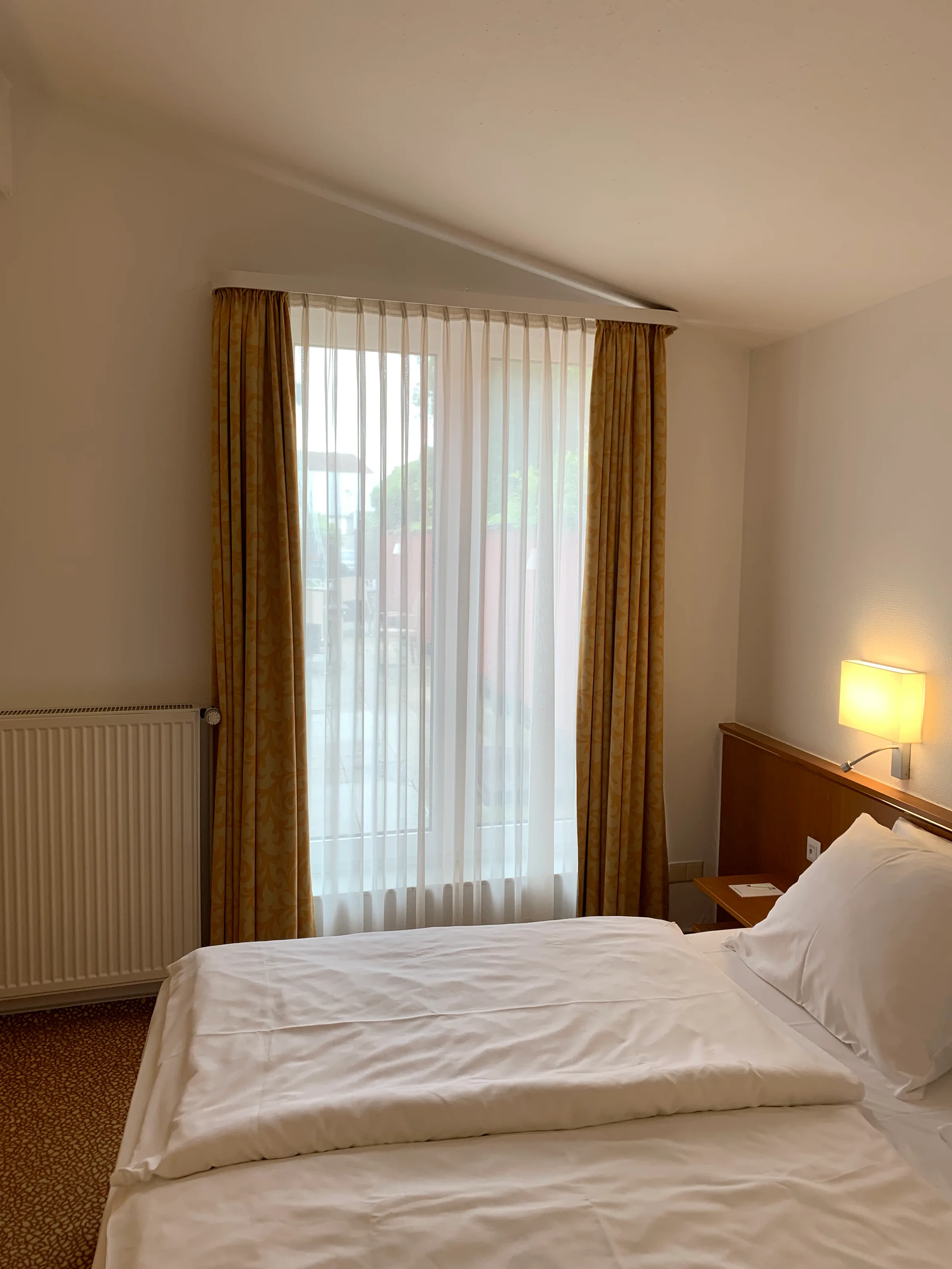 Hotelzimmer mit Doppelbett und Vorhängen in Grautönen