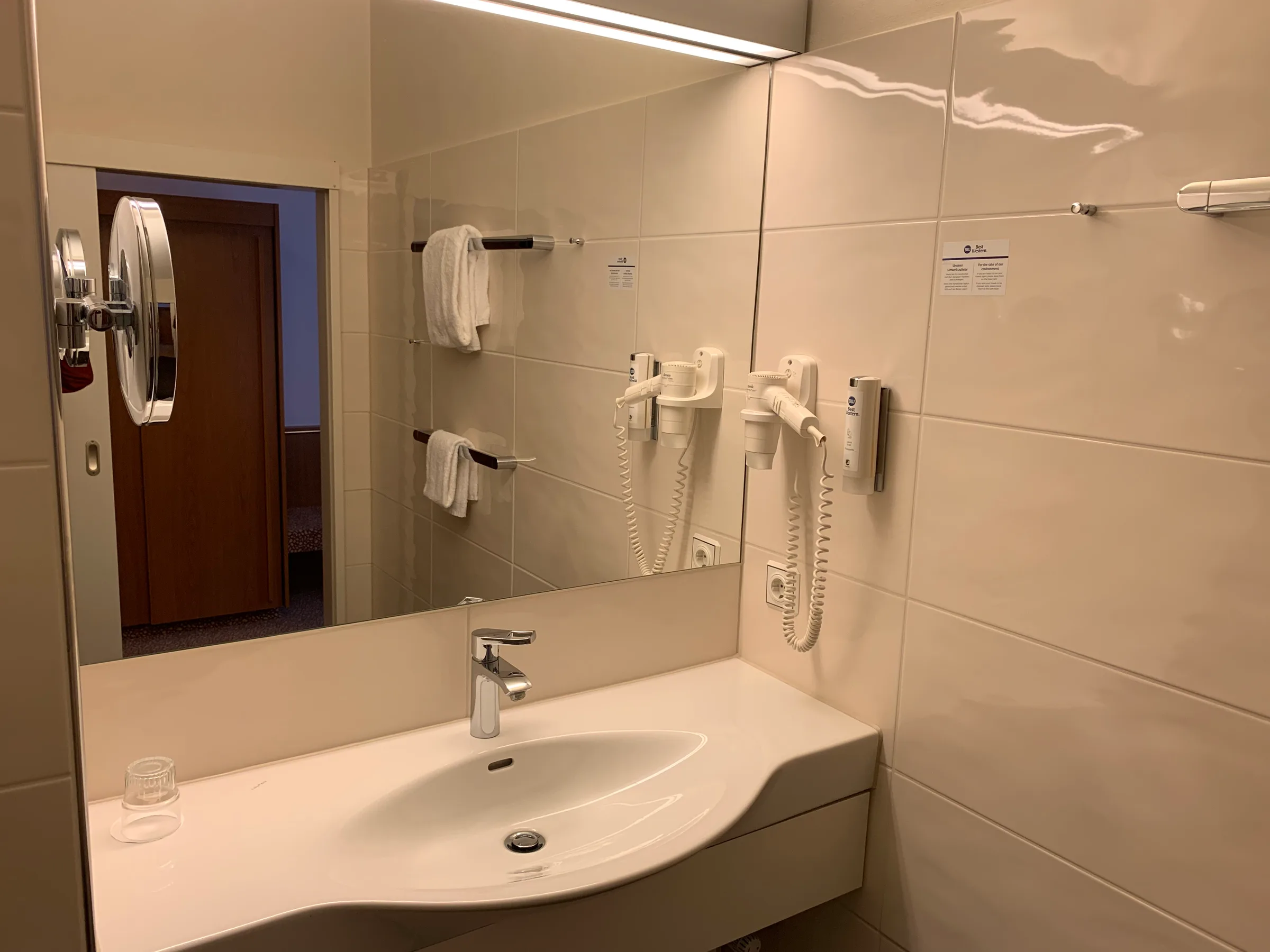 Hotelbadezimmer mit Waschbecken, Spiegel und Handtuchhalter