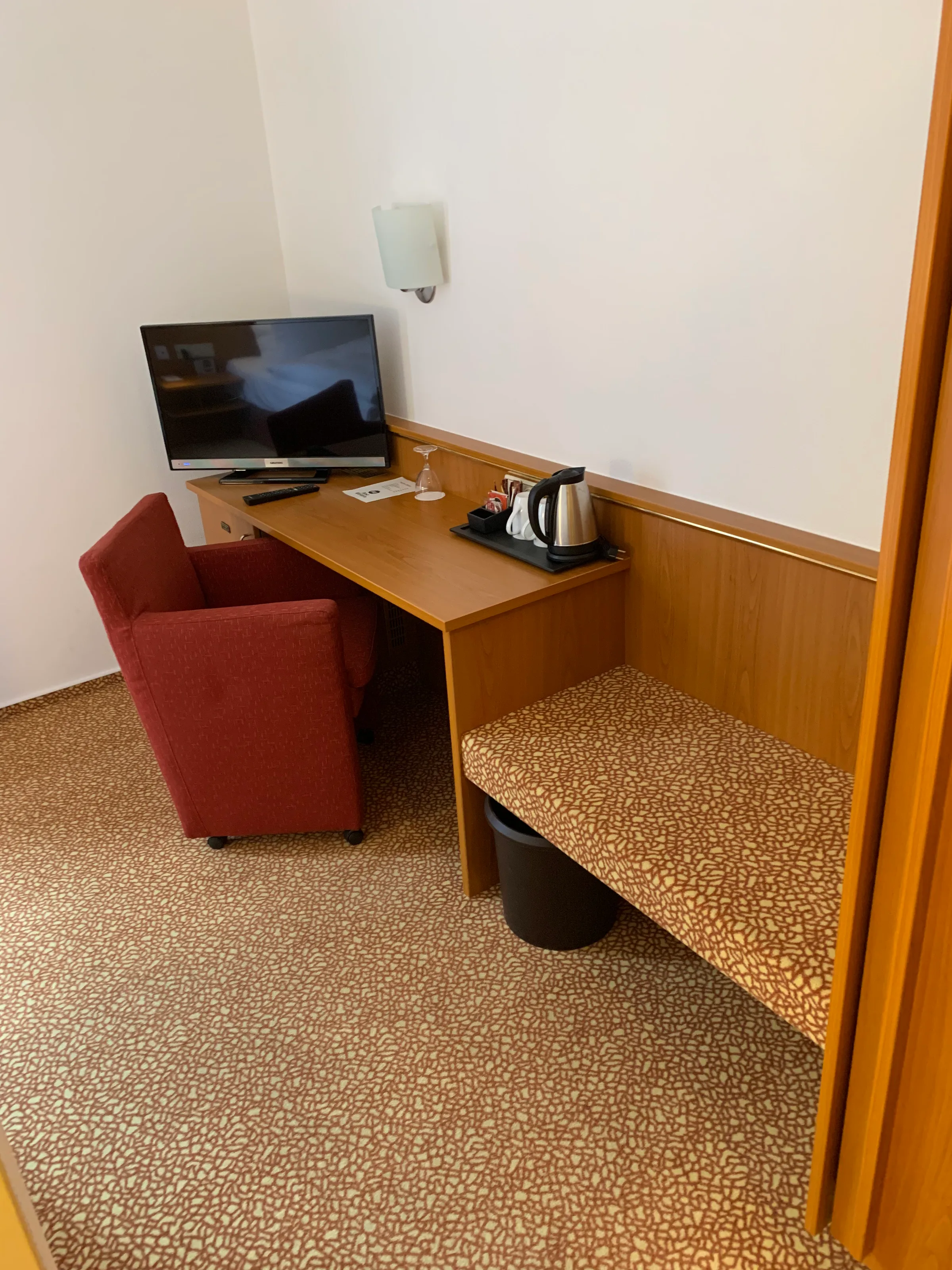 Hotelzimmer mit Schreibtisch, Stuhl und Fernseher