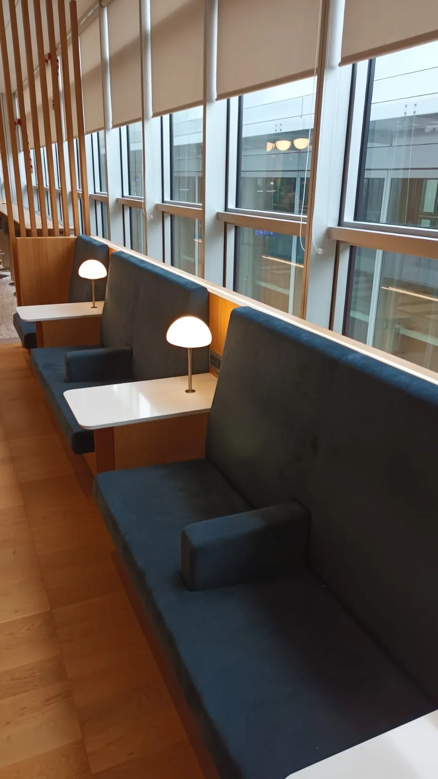 Lounge mit Sitzplätzen und Tischen vor großen Fenstern