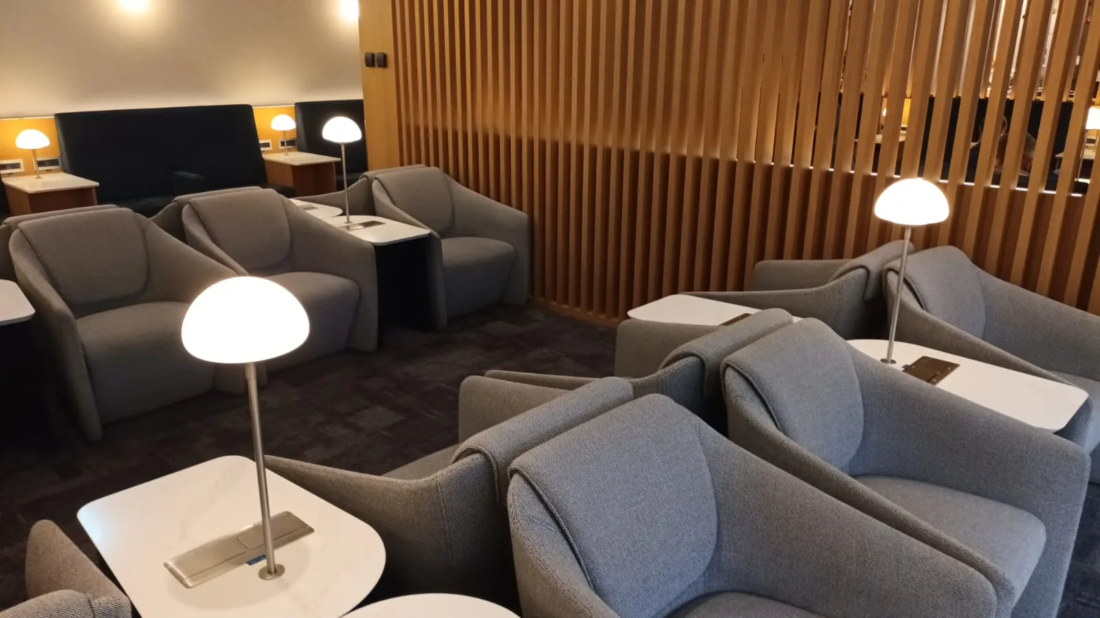 Graue Sessel und Couch im Loungebereich mit Holzwänden und Tischen