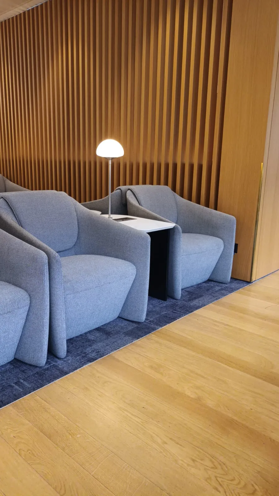 Zwei blaue Sessel mit Tisch und Stehlampe vor Holzwand