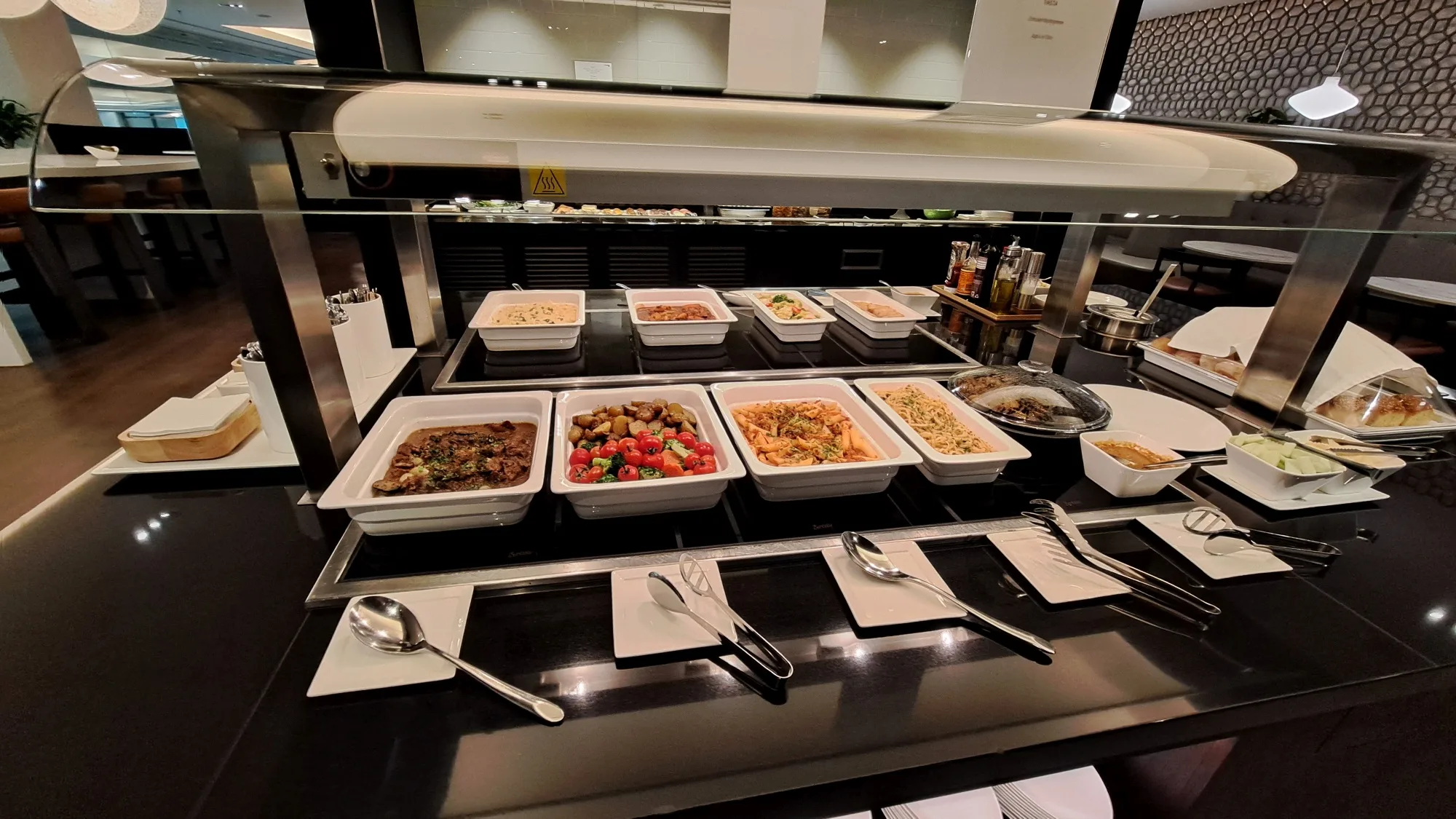 Buffet mit verschiedenen Gerichten in Schalen auf einem schwarzen Tisch