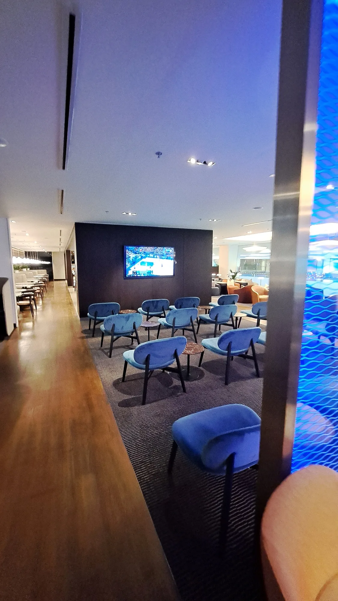 Lounge mit blauen Sesseln und Fernseher im Hintergrund