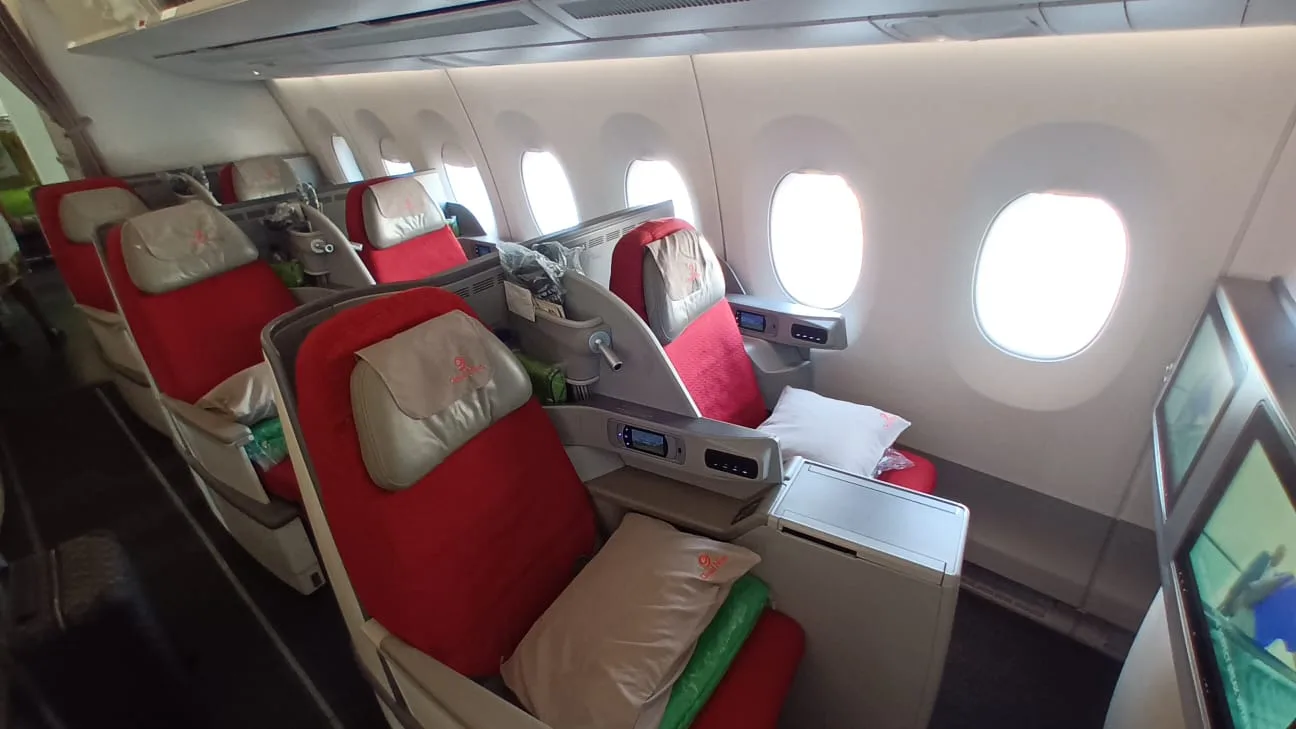 Business Class Sitzreihe mit roten Sitzen und Kopfstützen in einem Flugzeug