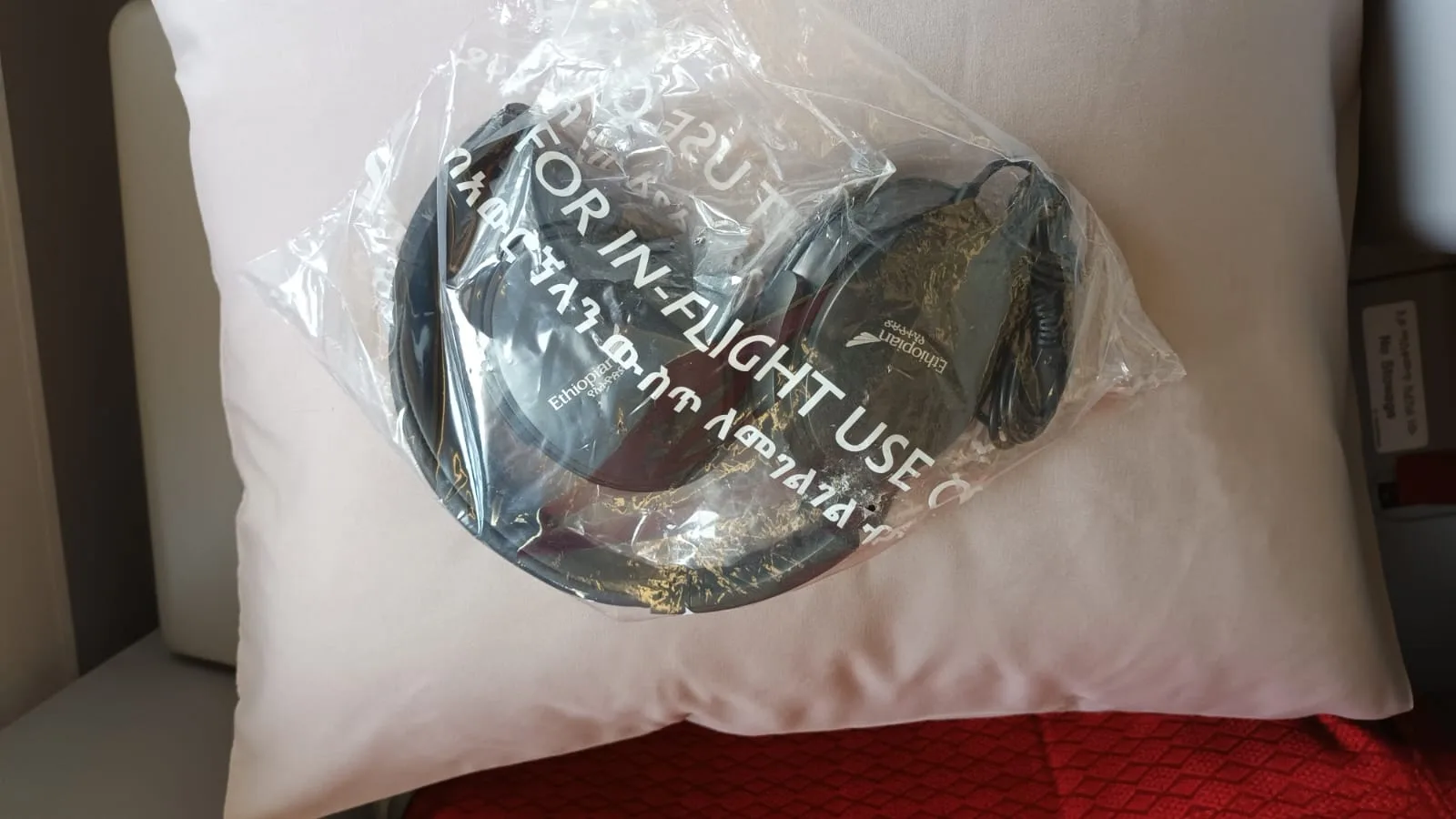 In-Flight Kopfhörer in Plastikverpackung auf Kissen