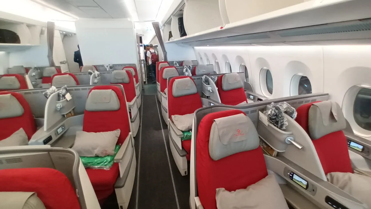 Business Class-Sitzreihen mit roten Polstern und Kopfstützen in einem Flugzeug