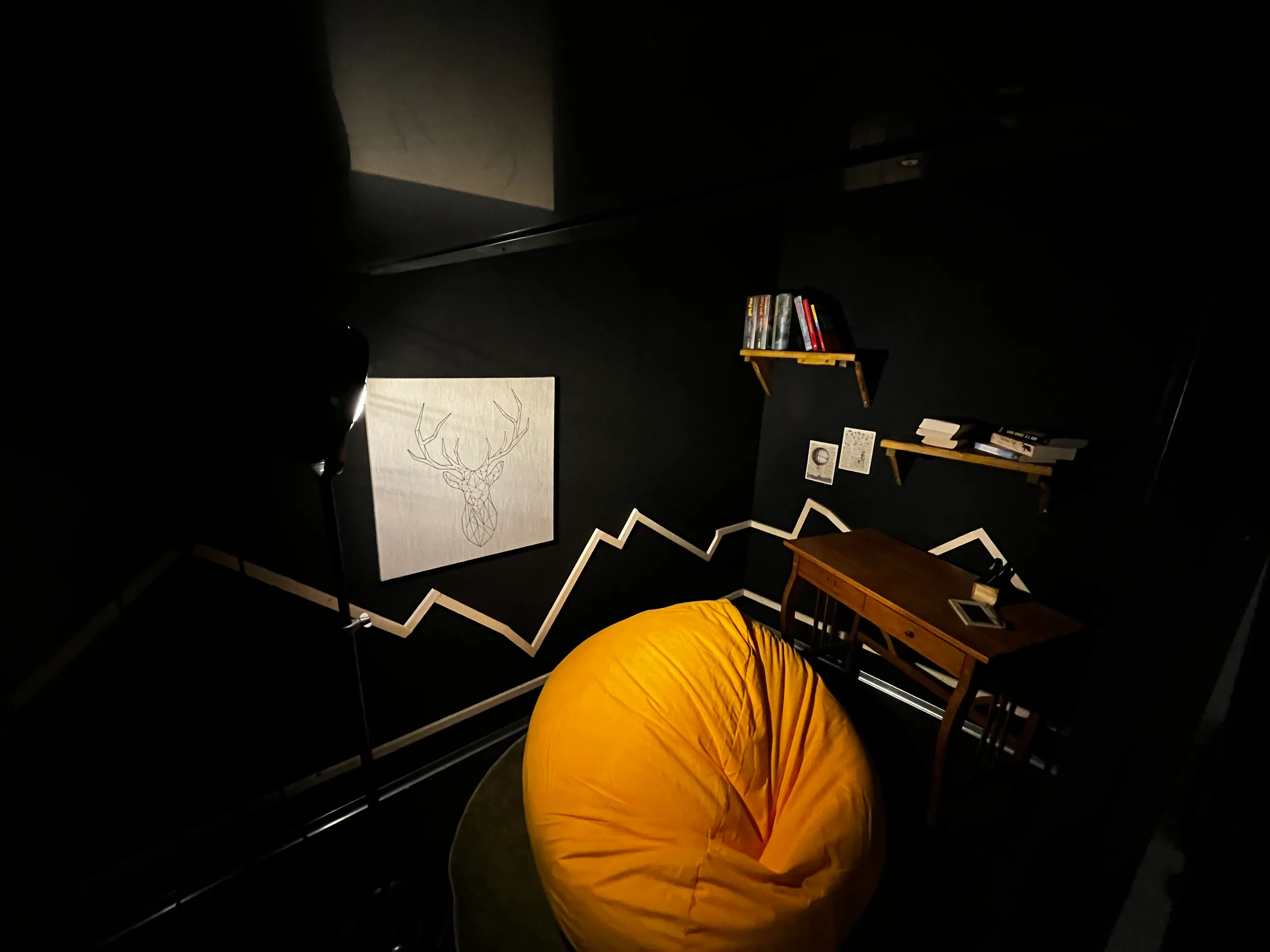 Schwarze Wand mit Bilderrahmen und Regal im dunklen Zimmer