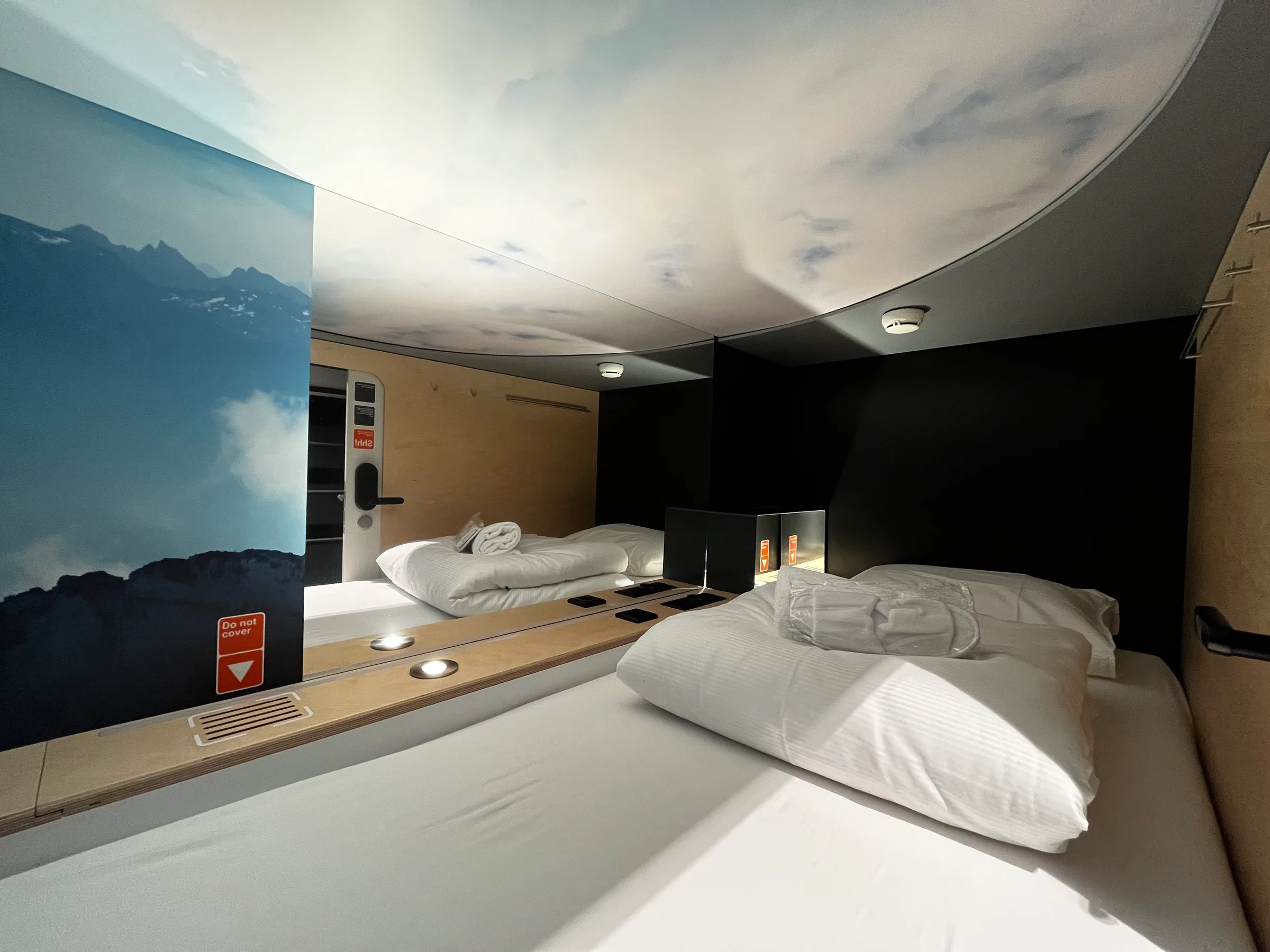 Hotelzimmer mit Doppelbetten und Wandbild von Bergen