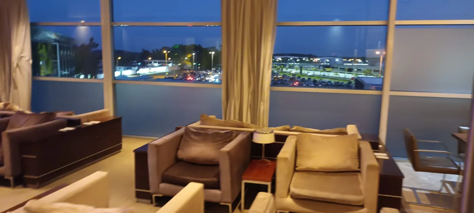 Lounge mit Sesseln und Tischen vor großen Fenstern