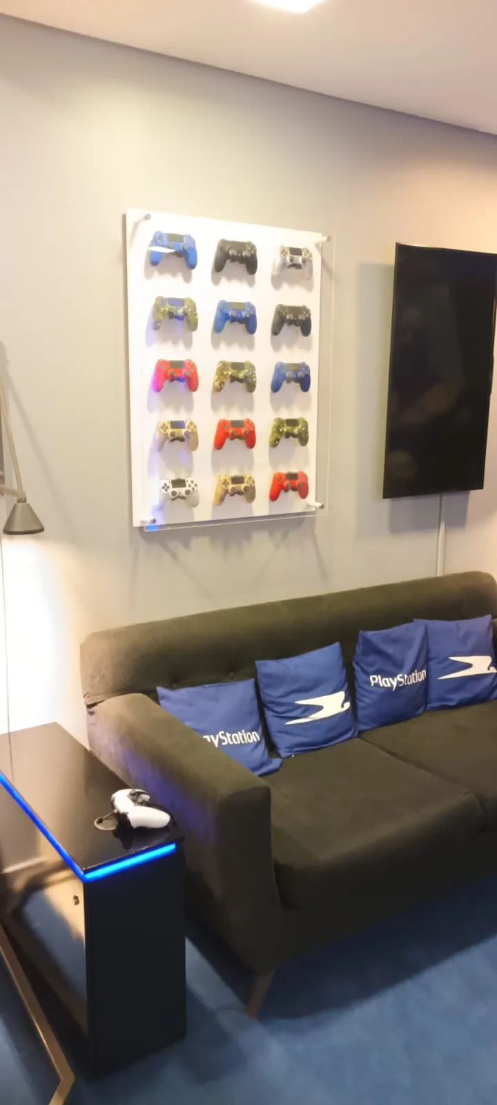 Sofa mit PlayStation-Kissen und Wandregal mit Controllern