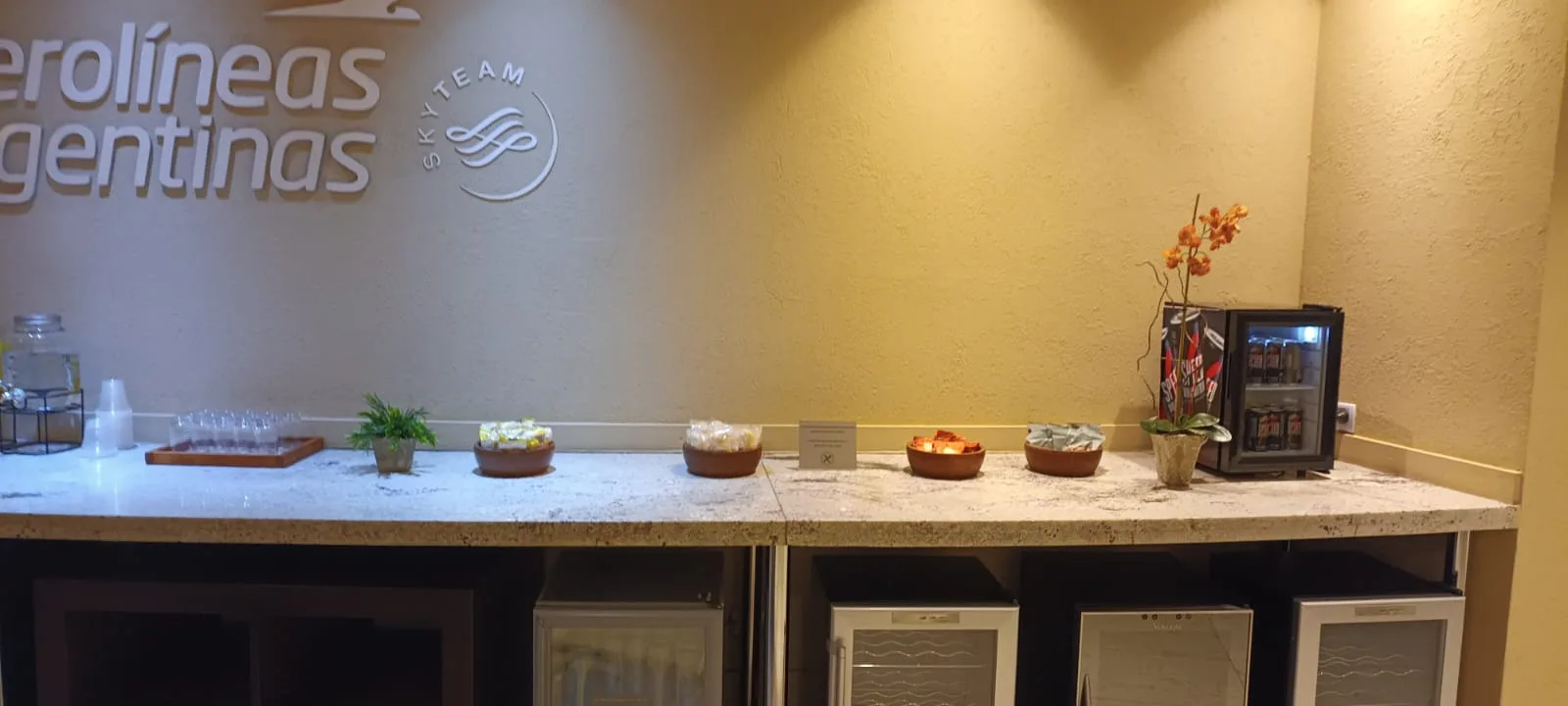 Lounge-Tisch mit Getränken und Snacks in der Condor Lounge von Aerolíneas Argentinas.
