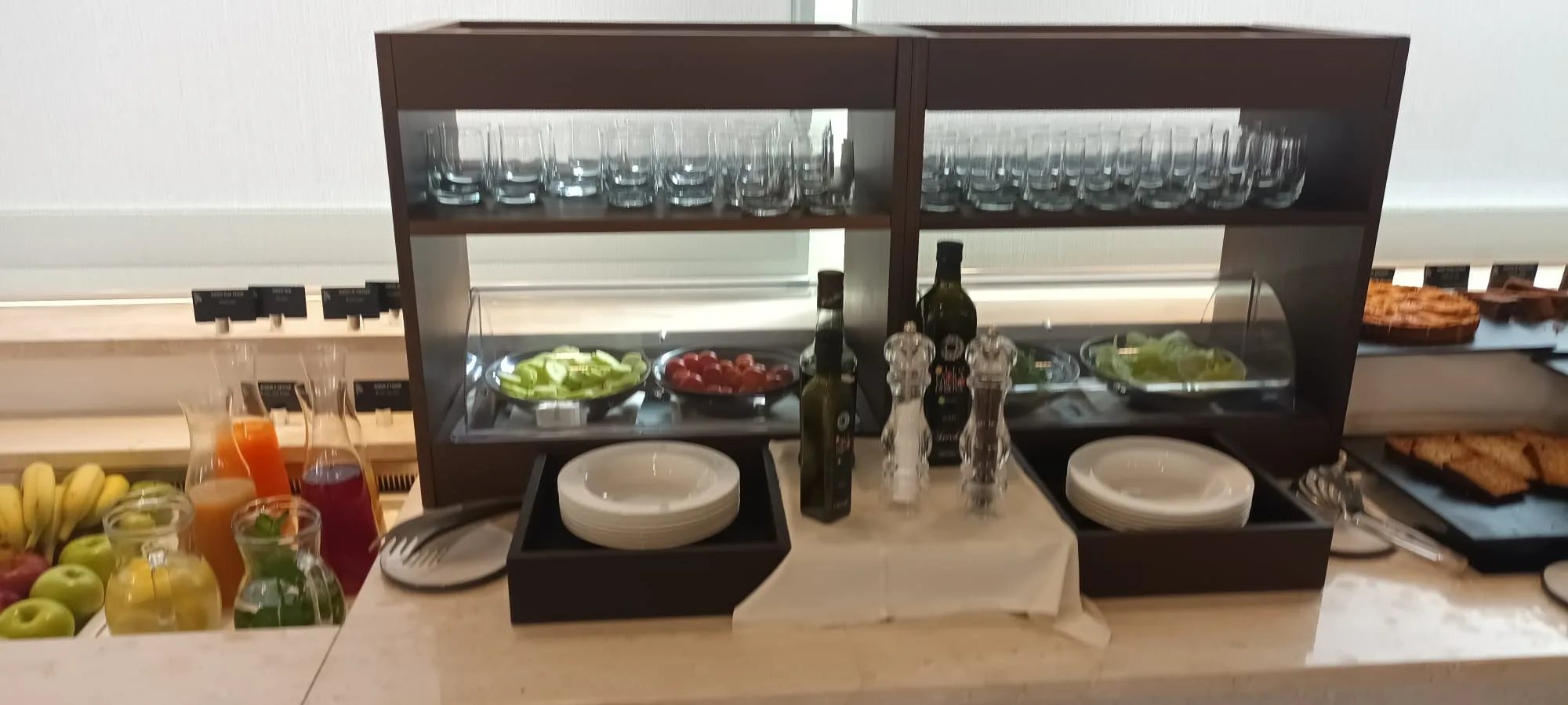 Buffet mit Salaten, Olivenölflaschen und Geschirr auf dem Tisch