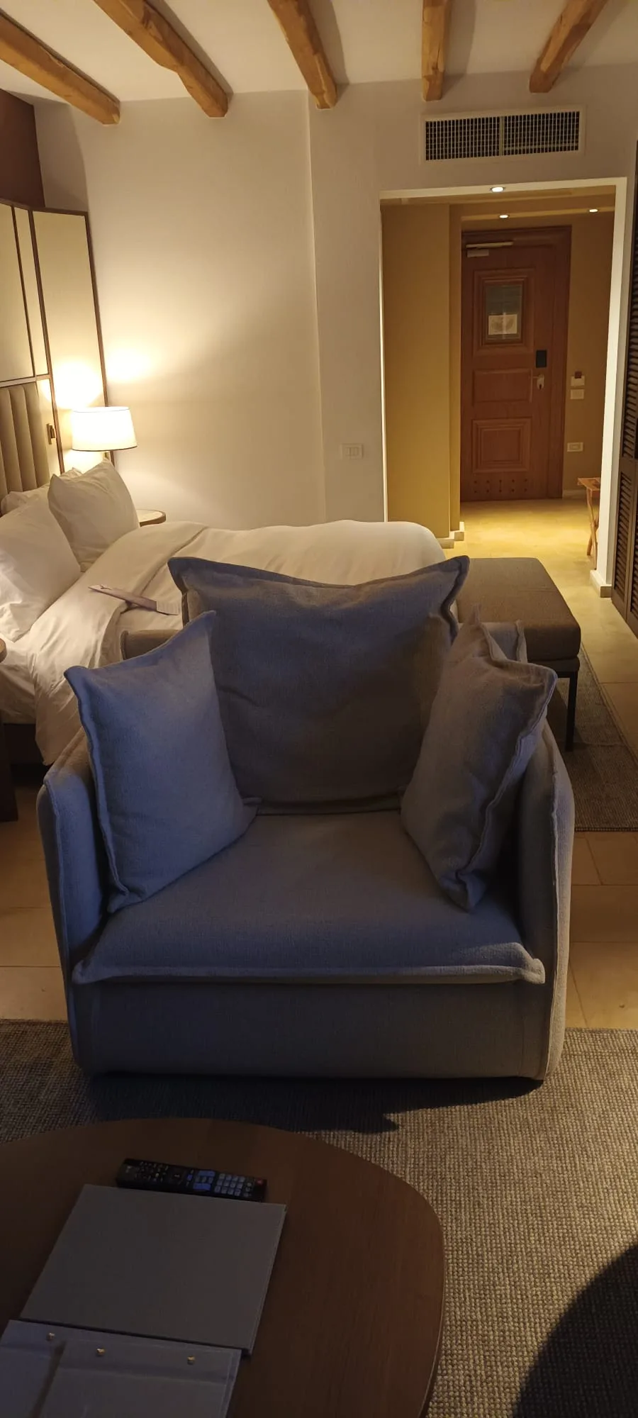 Hotelzimmer mit Sessel und Doppelbett in Grautönen