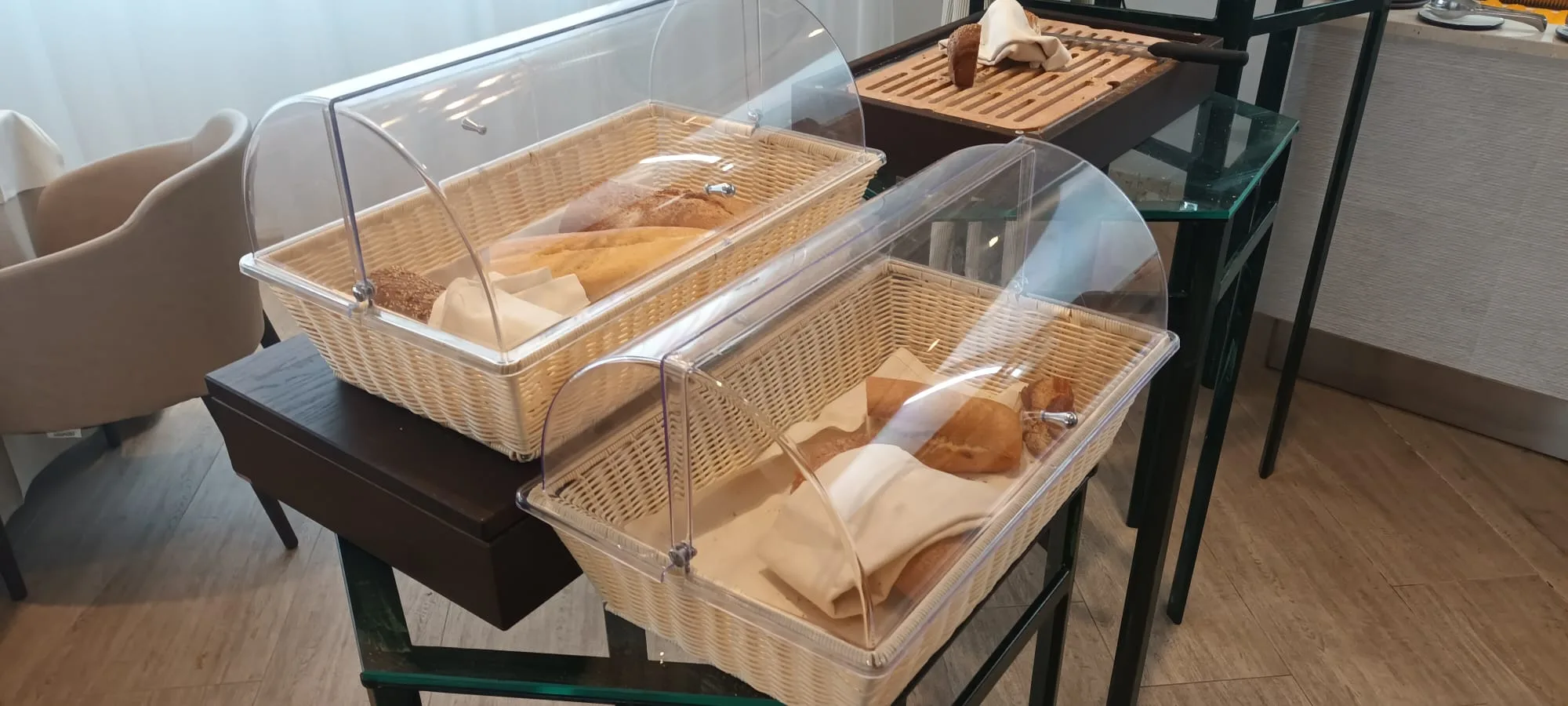 Brotkörbe mit Schutzkuppeln auf Tischen im Frühstücksbereich