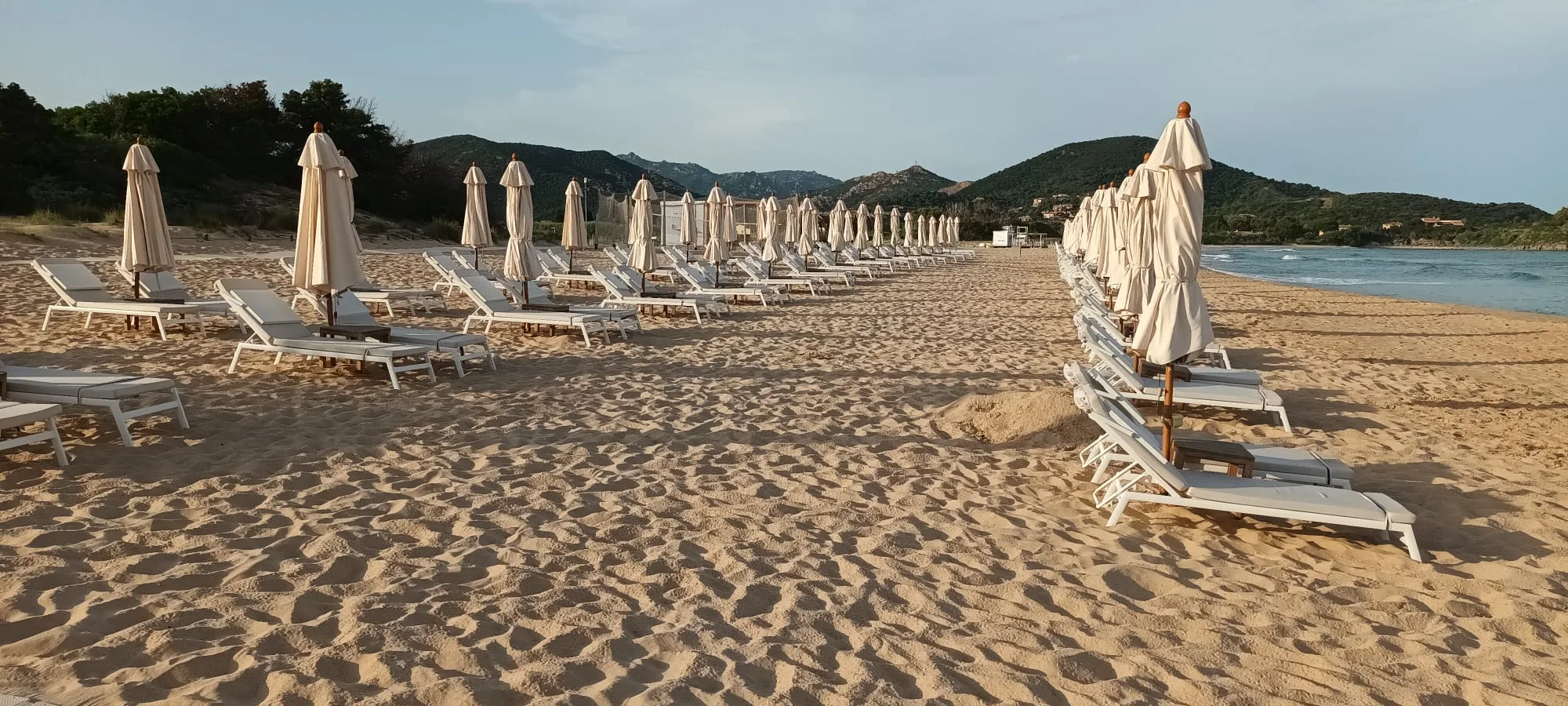 Strand mit Liegestühlen und Sonnenschirmen am Abendlicht
